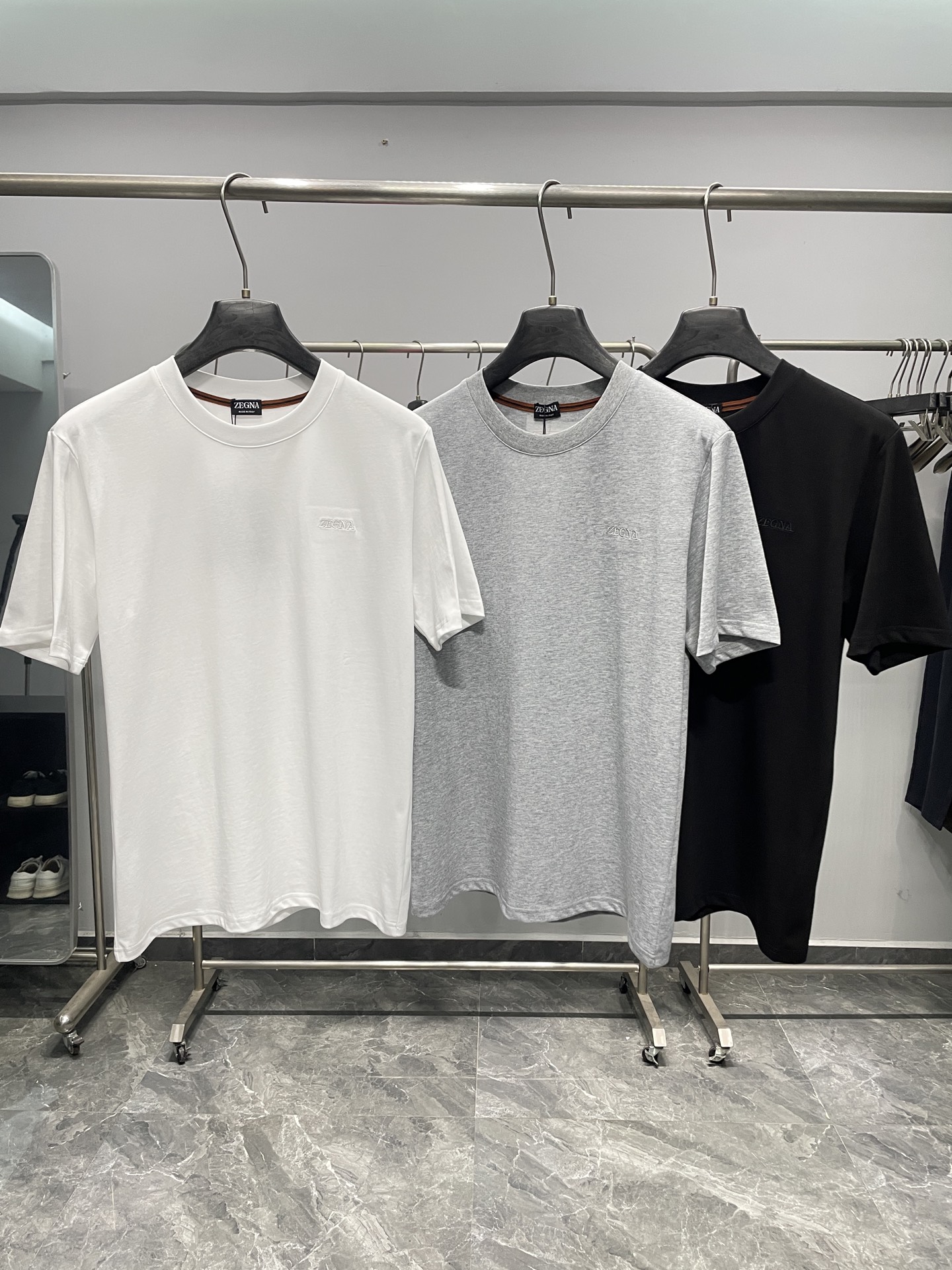 NO:777719,ZG26SS new spring and summer new jersey cotton basic round neck short Tee, men's classic letter logo embroidered casual pullover short-sleeved T-shirt!  Trading company channels are rare and available on the official website simultaneously!  Z's new basic short T-shirt shows its unparalleled luxury status with exquisite details, elegant fabrics and unique design elements!  This T-shirt is made of custom-made plain knitted cotton. The texture of the fabric is fine and even, and it feels soft and smooth, just like a baby's skin!  Moreover, this kind of cotton also has good breathability and moisture absorption. Even in the hot summer, you can feel refreshing and comfortable wearing it without feeling stuffy, allowing your skin to breathe freely!  The embroidery of the same-color letter logo on the chest is the finishing touch. The designer cleverly used the same-color matching principle to perfectly integrate the letter logo with the overall color of the T-shirt, which will not appear too ostentatious, but can also cleverly attract people's attention!  The embroidery craftsmanship is even more exquisite, and every stitch and thread is full of the hard work and wisdom of the craftsmen!  The two-color embroidered webbing element on the back collar is another highlight of the design that echoes the letter logo embroidery on the chest. It not only plays a decorative role, but the echoing design technique also reflects the designer's ingenuity, making the entire T-shirt look more harmonious and unified, highlighting the unique charm of the high-end luxury brand!  For a well-fitting cut, the designer fully considered the principles of ergonomics and carefully cut it according to the characteristics of different body types. Whether you have a slender figure or a plump figure, wearing this T-shirt can show the best body proportions!  Color White, Gray, Black Size S-XXL Size Reference S Size Shoulder Width 45 Bust Length 67 M Size Shoulder Width 46 Bust 104 Length 68 L Size Shoulder Width 47 Bust 108 Length 69 XL Size Shoulder Width 48 Bust 112 Length 70 219860909ZG26SS春夏新款平纹针织棉布基础圆领短Tee,男士经典字母徽标刺绣休闲套头短袖T恤衫！贸易公司渠道稀出,同步官网发售！Z家新款基础短Tee以精致的细节、考究的面料和独特的设计元素,展现出了无与伦比的高奢身份！ 这款T恤选用客供定制平纹针织棉布,面料纹理细腻、均匀,触感柔软顺滑,仿佛婴儿的肌肤一般！而且这种棉布还具有良好的透气性和吸湿性,即使在炎热的夏日,穿着它也能感受到清爽舒适,不会产生闷热感,让肌肤能够自由地呼吸！胸前衣身同色系字母徽标刺绣堪称点睛之笔,设计师巧妙地运用了同色系的搭配原则,将字母徽标与T恤的整体颜色完美融合,既不会显得过于张扬,又能巧妙地吸引人们的目光！刺绣工艺更是精湛绝伦,每一针每一线都饱含着工匠们的心血和智慧！ 而后领的双色刺绣织带元素,则是与胸前字母徽标刺绣相呼应的又一亮点设计,它不仅起到了装饰的作用,前后呼应的设计手法,更是体现了设计师的匠心独运,让整个T恤看起来更加和谐统一,彰显出高奢品牌的独特魅力！合身的版型裁剪,设计师充分考虑了人体工程学原理,根据不同身材的特点进行了精心裁剪,无论是修长的身材还是较为丰满的体型,穿上这款T恤都能展现出最佳的身材比例！ 颜色白色、灰色、黑色 尺码S-XXL 尺寸参考 S码肩宽45胸围衣长67 M码肩宽46胸围104衣长68 L码肩宽47胸围108衣长69 XL码肩宽48胸围112衣长70 2XL码肩宽49胸围116衣长71,,T-shirt,tees，t-shirt,,Men's clothing