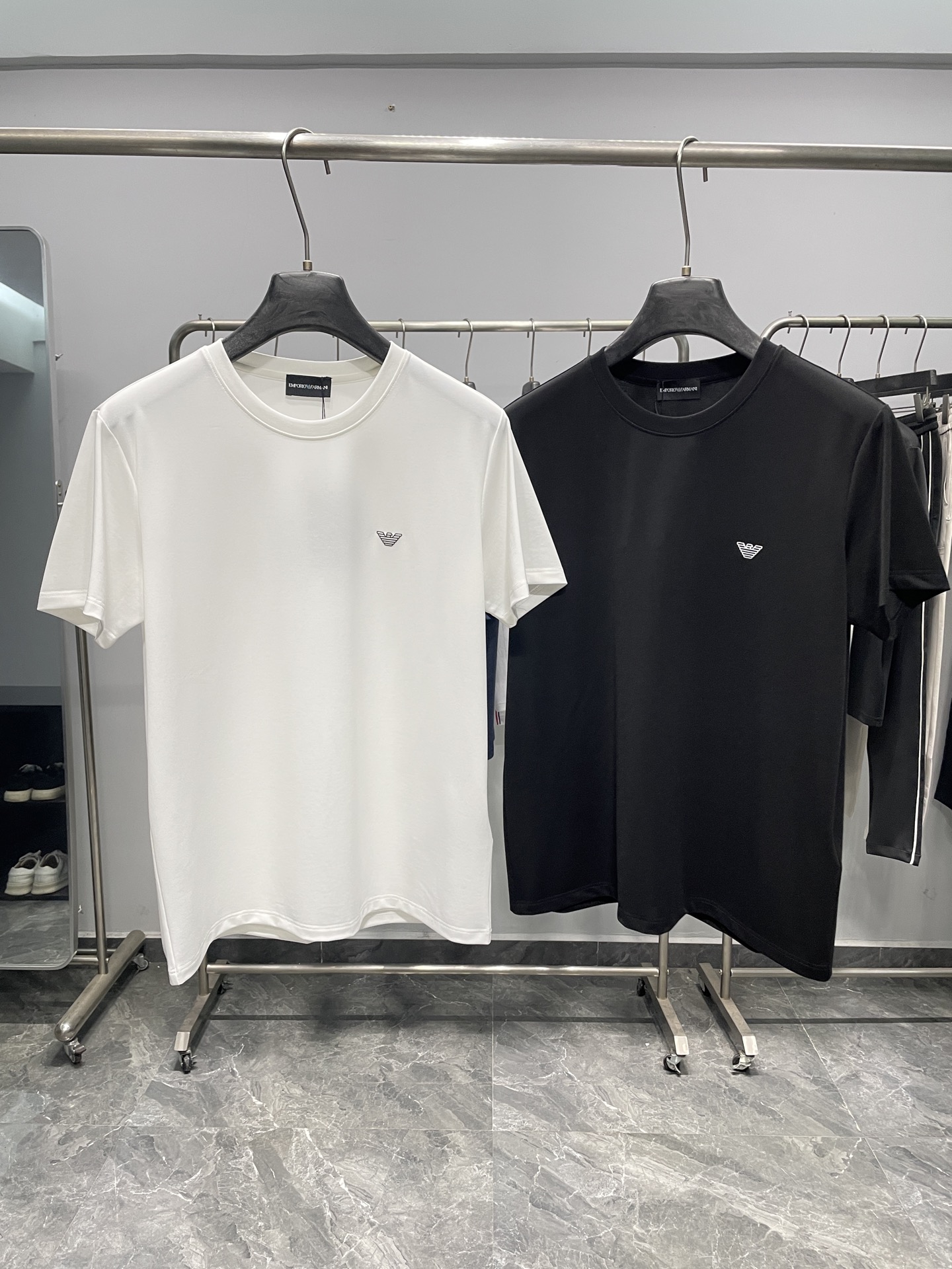 NO:777742,EA26SS spring and summer new lightweight technical stretch cotton round neck short Tee, men's classic eagle logo offset casual pullover short-sleeved T-shirt!  Trading company channels are rare and available on the official website simultaneously!  On the fashion stage, there are always some items that can stand out with their unique design and excellent quality, and the EA Eagle logo T-shirt is one of them!  When you first see it, you will be deeply attracted by the unique charm it exudes!  This T-shirt is made of customized technical stretch breathable cotton fabric. It has gone through countless R&D and improvements and incorporates advanced mesh structure technology elements!  When you touch it gently, the touch is as smooth as touching soft silk, delicate and smooth, making people unable to put it down!  It is also very thin and light, and you can hardly feel the weight when wearing it, as if it has covered your body with a layer of light clouds, without any burden!  Not only that, this fabric also has excellent elasticity. Whether you are doing extensive stretching or intense exercise, it can fit your body closely without feeling restrained, allowing you to move freely!  The classic eagle logo on the chest embellishes the brand's culture and spirit!  Through the three-dimensional offset printing process, the eagle logo seems to have vitality. It is slightly raised from the surface of the T-shirt and has a full three-dimensional effect!  Fitted cut, it can fit the curves of the human body well and show off the wearer's figure advantages!  This fitted version also has a certain degree of tolerance. It is not too tight and makes people feel uncomfortable, nor is it too loose and looks bloated. It is truly both fashionable and comfortable!  Color White, Black Size S-XXL Size Reference S Size Shoulder Width 44 Bust 104 Length 65 M Size Shoulder Width 45 Bust Length 66 L Size Shoulder Width 46 Bust 112 Length 67 XL Shoulder Width 47 Bust 116 Length 68 219860909EA26SS春夏新款轻薄科技弹力棉布圆领短Tee,男士经典老鹰徽标胶印休闲套头短袖T恤衫！贸易公司渠道稀出,同步官网发售！在时尚的舞台上,总有一些单品能够凭借独特的设计与卓越的品质脱颖而出,EA老鹰徽标T恤便是其中之一！当你第一眼看到它,就会被它所散发的独特魅力深深吸引！ 这款T恤采用了客供定制的科技弹力透气棉布,经过了无数次的研发与改良,融入了先进的网眼结构科技元素！当你轻轻触摸它时,那种触感丝滑得如同抚摸在柔软的丝绸上,细腻而顺滑,让人爱不释手！并且还十分轻薄,穿在身上几乎感觉不到重量,仿佛给身体披上了一层轻盈的云朵,毫无负担感！不仅如此这种面料还具有出色的弹力性能,无论你是做大幅度的伸展动作,还是进行激烈的运动,它都能紧密贴合身体,不会产生束缚感,让你自由自在地活动！胸前经典的老鹰徽标点缀,承载着品牌的文化与精神！通过立体胶印工艺,老鹰徽标仿佛具有了生命力一般,从T恤表面微微凸起,立体感十足！合身版型裁剪,它能够很好地贴合人体的曲线,展现出穿着者的身材优势！这种合身版型还具有一定的包容性,不会过于紧身而让人感到不适,也不会过于宽松而显得臃肿,真正做到了既时尚又舒适！ 颜色白色、黑色 尺码S-XXL 尺寸参考 S码肩宽44胸围104衣长65 M码肩宽45胸围衣长66 L码肩宽46胸围112衣长67 XL码肩宽47胸围116衣长68 2XL码肩宽48胸围120衣长69,,T-shirt,tees，t-shirt,,Men's clothing