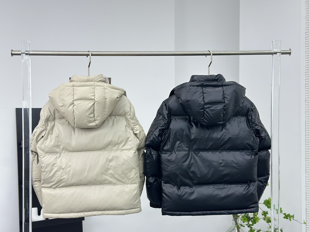 Prada 普拉达黑科技压胶羽绒服

秋冬新款高密度哑光漆面尼龙羽绒夹克，男女同款金属三角大标口袋可拆卸连帽立领羽绒服外套!贸易公司渠道稀出，同步官网发售!
P家新款羽绒服在保暖性能和时尚设计之间取得了完美平衡，并且成为2024年秋冬季街头潮流中的亮点!

它采用了精选客供进口高密度哑光漆面尼龙材质，让面料表面纹理细腻清晰，呈现出肉眼可见的高级质感!不仅如此这款外套还具备防风、防水、耐磨和防撕裂等功能性，超级出色!在内里方面，采用了高含量欧标羽绒，并结合横向绗缝工艺进行分格填充，使得整体保暖蓬松且不显臃肿感!胸前口袋上的硕大三角标金属徽章装饰简约大气，将奢华身份展露无遗!这款外套还特别定制了刻有品牌字样的哑光漆面金属拉链，并经过全压胶处理，品相细节无法挑剔，设计上采用可拆卸式连帽立领造型，搭配基础直筒版型剪裁，上身既保暖又不挑风格与造型!男女同款推荐，不失任何年龄阶段的限制，在时尚圈引起一番热议!