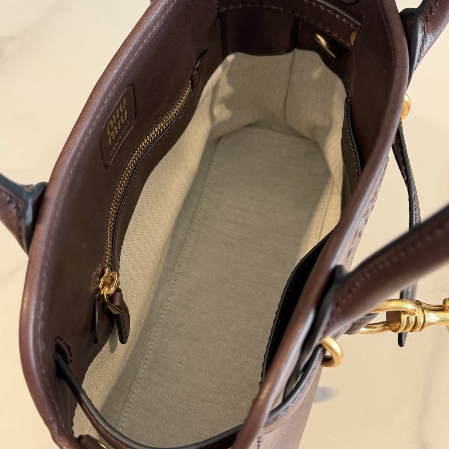 P770 Mi* Mi* 26ss Aventure 采用全新植柔羊皮，皮质柔软高级，Aventure Nappa皮革手袋灵感源自Miu典藏设计，结构经过调整，小版比例更为精致，变得更加轻便，焕发全新个性，饰以压花字母徽标，增添标志性元素，复古金色五金配件，亚麻混纺衬里，配拉链口袋和贴袋，增加长肩带使用更便利，手腕适合用作手提或单肩，
型号：5BA292～
尺寸：30*22*10cm