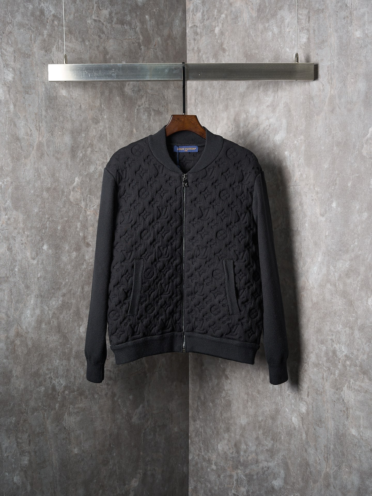 【实物挂拍】LV/路易威登 Monogram绗缝立体浮雕衬垫羊毛飞行员拉链夹克外套 【现货】S M L XL 定织臻选羊毛交织立体提花料 柔如云朵 厚重扎实 每一寸纤维都蕴含着沉甸甸的暖意 经典黑色调散发与生俱来的高级感 以全幅Monogram绗缝重构衣身肌理 每一道菱形格将帆布上的平面图腾重塑为衣身的浮雕建筑 深浅不一的纹理如同浮雕般凸起 用纹路撑起的利落骨架 绗缝衬垫 重构飞行员夹克的温度哲学 让标志性符号成为行走的艺术 模塑立体Monogram压花工艺 永久定型浮雕轮廓 优先通过定制金属模具与精密压合技术 将Monogram图案以浮雕式立体纹理永久定型 形成兼具视觉凹凸感与触觉浮雕感的立体纹路 采用激光投影定位系统 将拆分的模具模块按Monogram排列规律在面料上精准对位 确保全幅图案连续无错位 多层复合衬垫 通过精准复合粘合衬+弹性海绵+隔离膜 三层功能性材料 形成面料 衬垫 里布的结构支撑 确保模压时Monogram纹路能立体隆起并永久定型 形态固定 成衣洗水加软去味工艺 通过专业的洗涤设备和特定的洗涤剂 对衣物进行深度清洁和去味处理 改善衣物的手感和外观,宽松版型