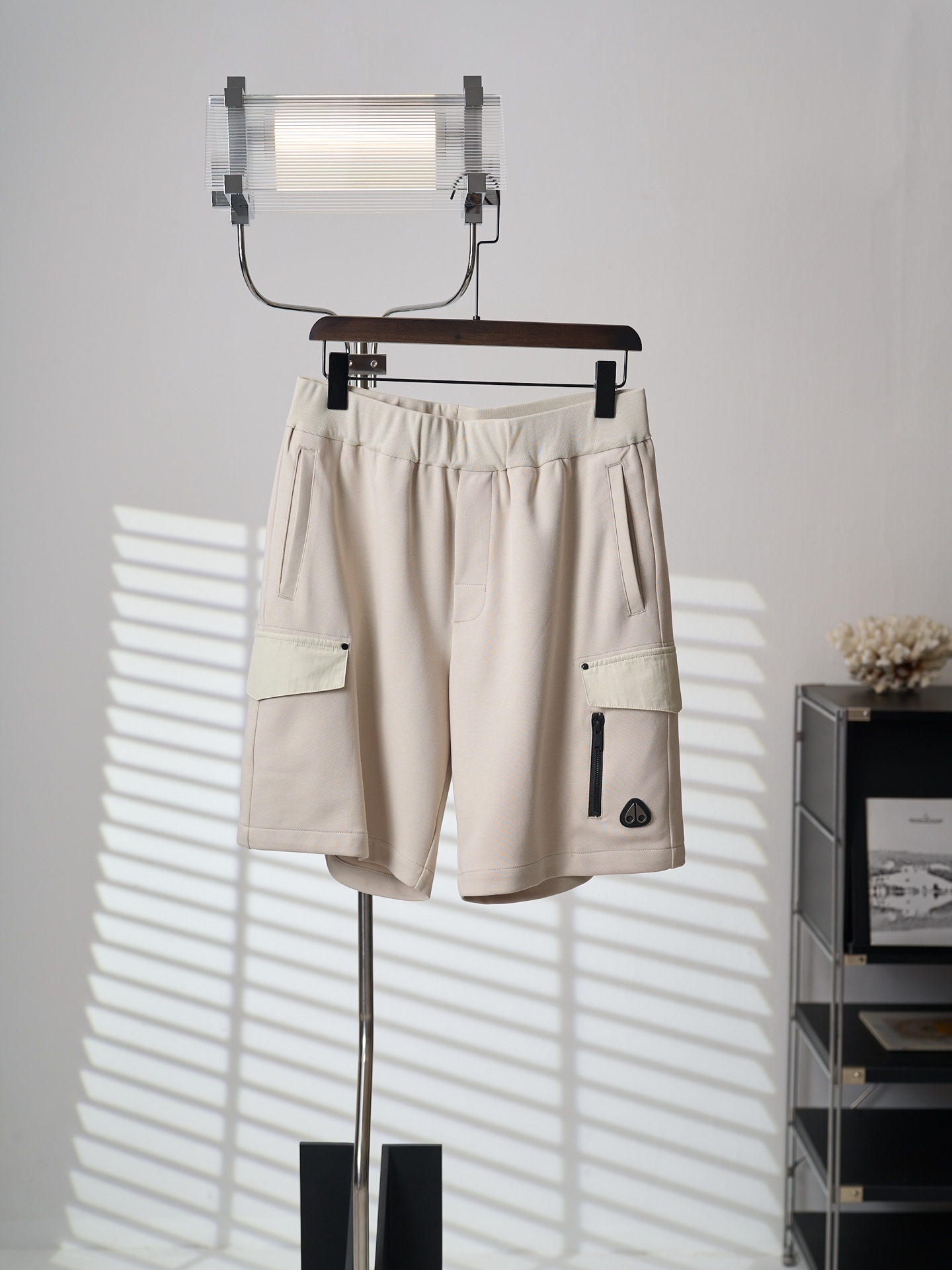 NO:931779,[Real object hanging] Moose Knuckles/Scissors work style cotton shorts [Ready stock] S M L XL fabric selection  Selected heavyweight combed double-yarn knitted cotton fabric has been pre-washed and sanded and air-softened to create a unique soft and crisp fabric feel. The fabric surface is fine and flat, the knitted texture is tight but not loose, and the surface has a matte soft texture. The high-weight specifications have natural drape, and the upper body is not easy to collapse and stick to the legs. At the same time, it has excellent natural breathable and moisture-conducting properties. It can quickly wick moisture away from the crotch when you sweat in summer, and you will not be bothered by hot and sticky body after sitting for a long time.  Pre-shrunk treatment: The whole width has been pre-shrunk and washed, which greatly avoids the problems of washing shrinkage and stiff fabrics. The trouser legs will not shorten and the waist will not bulge after repeated washing. The knitted cotton is blessed with anti-pilling technology and will not easily form white lint balls due to daily friction. Cut pieces  The main body of the trousers is precisely divided into pieces using a CNC cutting machine, and the error of the left and right trousers is controlled at the millimeter level to ensure left and right symmetry of the garment; the flaps of the work pockets on both sides are made of woven pieces of the same color, which is different from knitted fabrics and can better adhere to the trousers without being obtrusive. Details  1. The top of the bag cover is reinforced with metal rivets, and the side of the bag is equipped with a customized waterproof zipper. The zipper is lined with a non-woven lining when sewing, so the zipper opening and closing will not tear the fabric of the bag mouth. The bottom of the bag is tightly sewn and hemmed, so it is not easy to collapse or crack when loading heavy objects.  2. The waistband has built-in high-elastic rib knitting, and the waistband is widened to fit the waistline without tightening the abdomen. It is matched with thick cotton ropes of the same color. The rope holes are overlocked and the drawstring straps are not easy to wear the fabric. The inner waistband is overlocked and the raw edges are fully stored. It is close to the skin and has no rough threads. 3. The hem of the trousers has double needles running in parallel, the width of the rolled edge is uniform and regular, and the double-thread seam reinforces the trouser cuff.,,shorts,19860909【实物挂拍】Moose Knuckles/剪刀 工装风棉质短裤 【现货】S M L XL 面料选择 精选重磅精梳双纱针织纯棉面料,经过预洗磨毛、空气柔化工艺处理,打造软糯兼具挺括的独特布感,布面细密平整,针织纹理紧实不松散,表层自带哑光柔润质感.高克重规格自带自然垂坠力,上身不易软塌贴腿,同时其天然透气导湿性能优异,夏日出汗快速排湿不闷裆,久坐无闷热黏身困扰.  预缩处理 全幅经过预缩水洗,大幅规避水洗缩水、面料发硬问题,反复洗涤裤腿不短缩、腰部不鼓包；针织棉抗起球工艺加持,日常摩擦不易起白絮小球. 裁片 主体裤身采用数控裁床精准分片,左右裤片误差控制在毫米级,保证成衣左右对称；双侧工装口袋翻盖选用同色系梭织裁片,区别于针织面料,能够更好贴附裤身,不突兀. 细节 1、袋盖顶端加装金属撞钉加固,口袋侧边搭配定制防水拉链,拉链车缝时内衬无纺衬,拉链开合拉扯不会撕裂袋口面料；袋底密缝锁边,装重物不易崩线开裂.  2、腰头内置高弹罗纹针织,加宽腰头贴合腰线不勒腹,搭配同色系加粗棉绳,绳孔做包边锁缝,抽拉绳带不易磨破布面；内里腰头包缝锁边,毛边全收纳,贴肤无粗糙线头. 3、裤脚下摆双针平行走线,卷边宽度统一规整,双线锁边加固裤口.,,shorts,,Men's clothing
