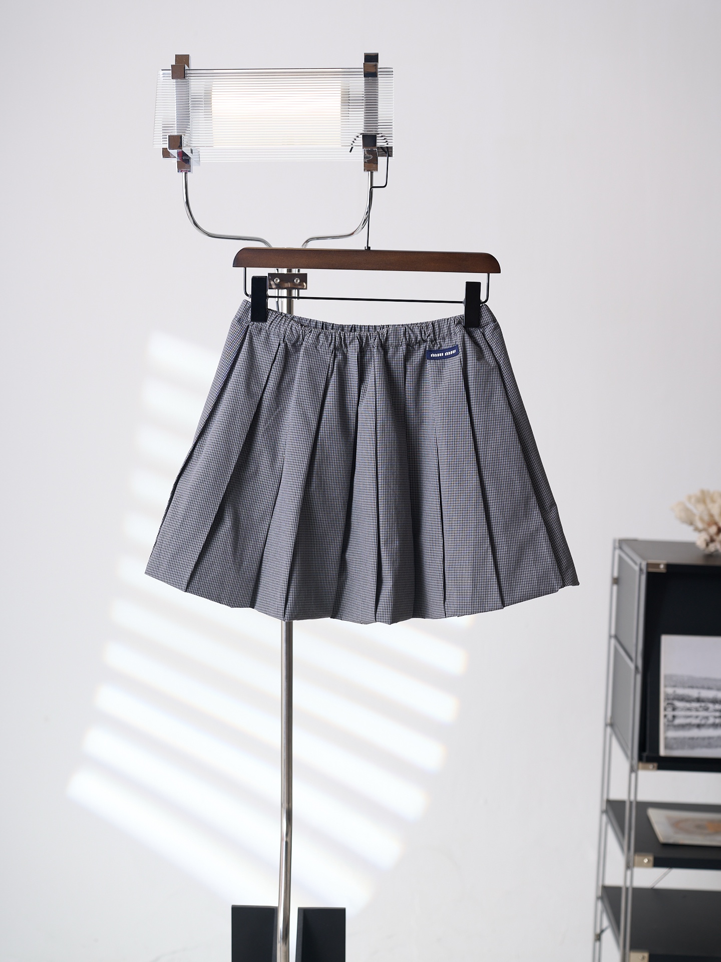 NO:936739,[Real auction] MiuMiu/Miu Miu matte gray plaid pleated skirt with logo [Ready stock] 38 40 42 Customized matte gray jacquard fine-lattice satin, draped and stiff, comfortable and close to the skin. The cool charcoal gray weave has a low-key base, and the fine native-dyed small plaid interweaves to create a layered texture, interpreting a cool retro low-saturation aesthetic.  The iconic MiuMiu label is low-key embellishment on the side, adding a low-key sense of luxury. With the classic and chic Vichy fine plaid as the design skeleton, the pleats naturally drape along the brown texture and swell into a bud silhouette, creating layers of ripple texture when you walk; the hip and leg lines are cleverly optimized to create a gold A-line shape that is narrow at the top and wide at the bottom. It is versatile and slim, creating a minimalist retro style model that will never go out of style. 1.  Special machine positioning adopts imported special machine infrared positioning 'MiuMiu label' to make the position more precise and firm. 2. CNC high-temperature integrated pleating relies on constant temperature stamping of high-precision molds to lock the fiber texture, insert the entire flat fabric into the mold, and synchronously press at constant temperature and high pressure, relying on heat to fuse the fiber structure of the fabric, allowing the pleat grooves and pleat surfaces to permanently form a physical memory, and pressing out all the pleats on the entire piece of fabric at the same time. 3. The accordion pleat waist binding strips are shaped  The special binding strips for the waist are wrapped and closed by professional pulling equipment. The cloth edges are wrapped tightly and fully, and are integrated with the elastic structure. The elastic stretch of the waistband is even, and the fit is perfect. Miumiu, skirts, gold,19860909【实物挂拍】MiuMiu/缪缪 雾碳灰徽标格纹百褶短裙【现货】38 40 42 定制雾炭灰缇织细格贡缎,垂坠挺括,舒适贴肤.清冷炭灰织就低调基底,细密原生色织小格纹交织出层次肌理,演绎清冷复古低饱和美学. 标志性MiuMiu标签低调点缀侧边,增添了一份低调的奢华感.以经典别致的Vichy维希细格纹为设计骨架,百褶顺着棕调肌理自然垂坠膨起成花苞廓形,走路时漾开层层涟漪质感；巧妙优化胯部与腿部线条,打造上窄下宽的黄金A字版型.百搭显瘦,打造永不过时的极简复古穿搭范本. 1. 专机定位 采用进口专机红外线定位“MiuMiu标签” 位置更为精准、牢固结实. 2. 数控高温一体压褶 依托高精度模具恒温冲压锁死纤维肌理,将整张平铺面料嵌入模具,通过恒温高压同步压制,依靠热力融合面料纤维结构,让褶沟、褶面永久形成物理记忆,一整片布同时压出全部褶裥. 3.风琴褶束腰捆条定型 腰位专用捆条经专业拉筒设备一体包合收边,布边包裹紧实饱满,结合松紧结构一体成型,腰头弹力伸缩均匀,合身版型,,miumiu,skirts,gold,,Men's clothing