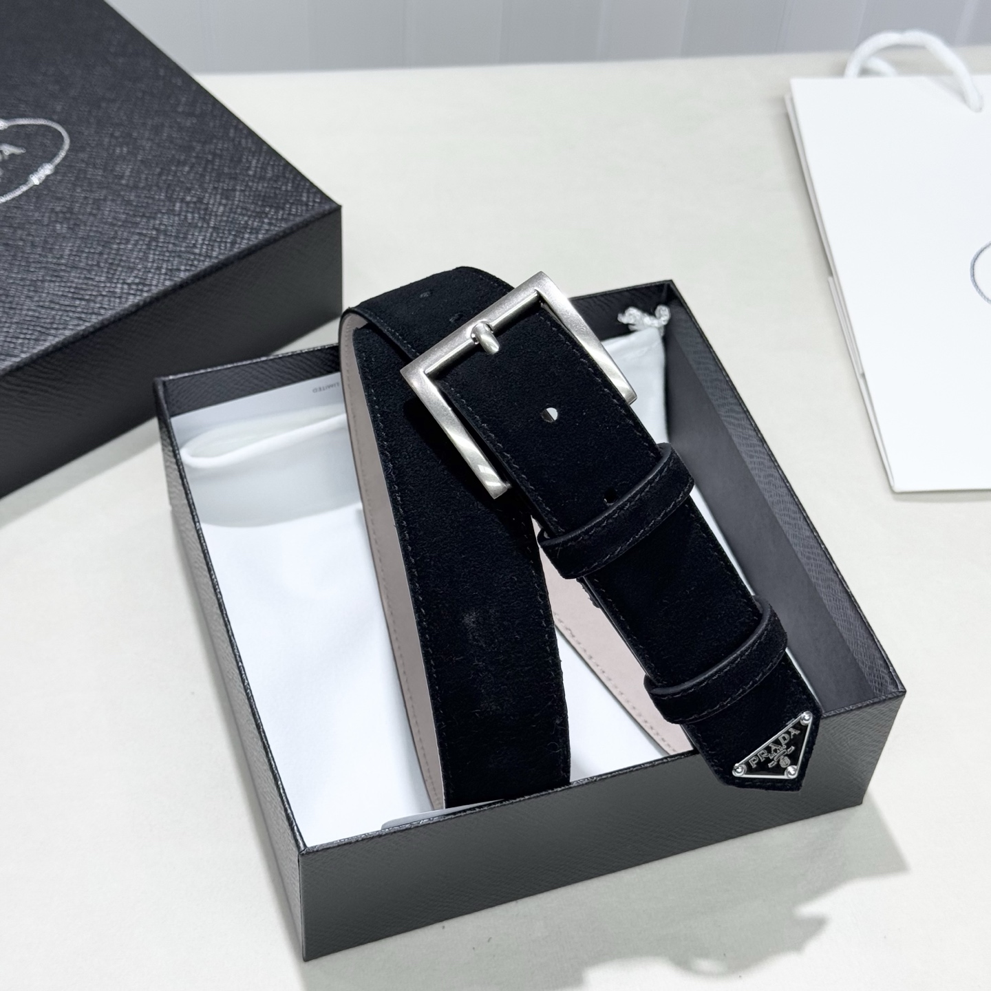 。 男女通用，P rada这款华美的绒面皮革腰带释放简约而精致的优雅气息 尖部的涂珐琅金属三角形徽标展现