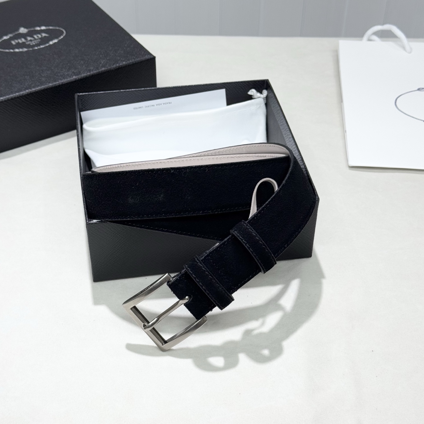 。 男女通用，P rada这款华美的绒面皮革腰带释放简约而精致的优雅气息 尖部的涂珐琅金属三角形徽标展现