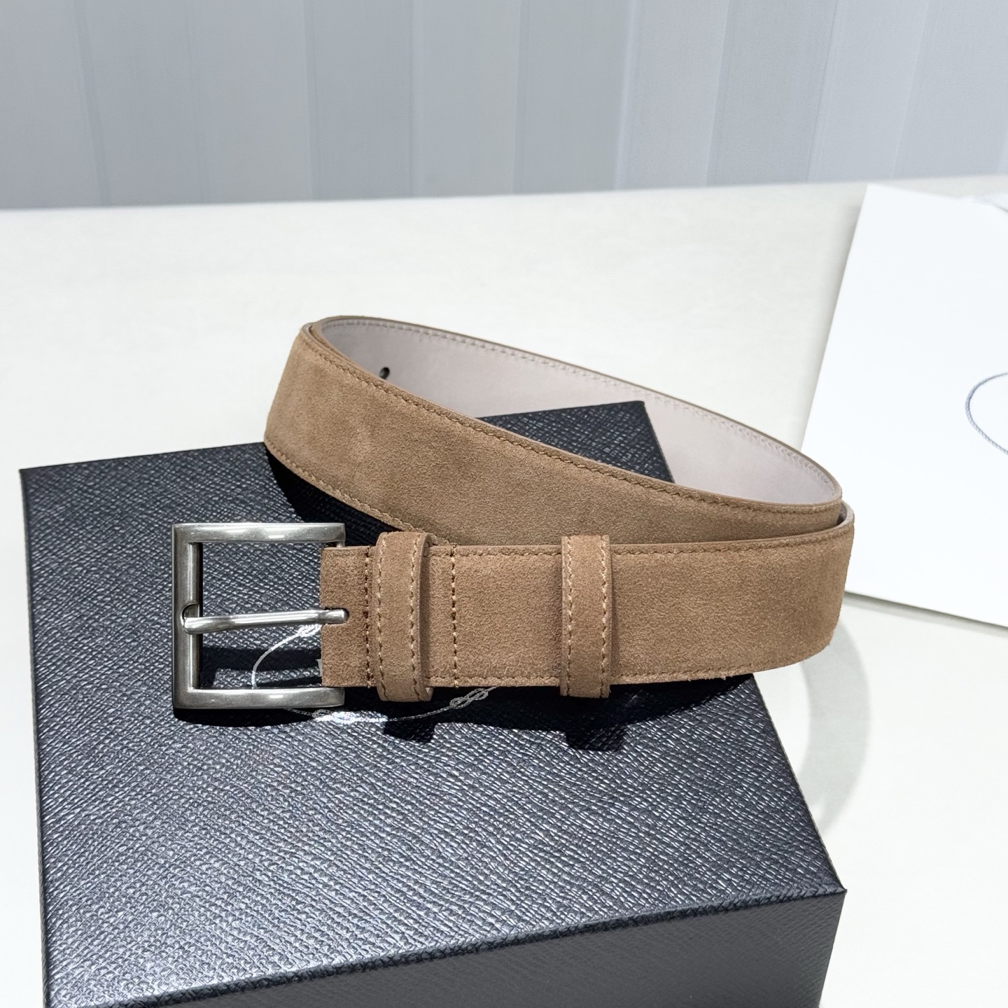 。 男女通用，P rada这款华美的绒面皮革腰带释放简约而精致的优雅气息 尖部的涂珐琅金属三角形徽标展现