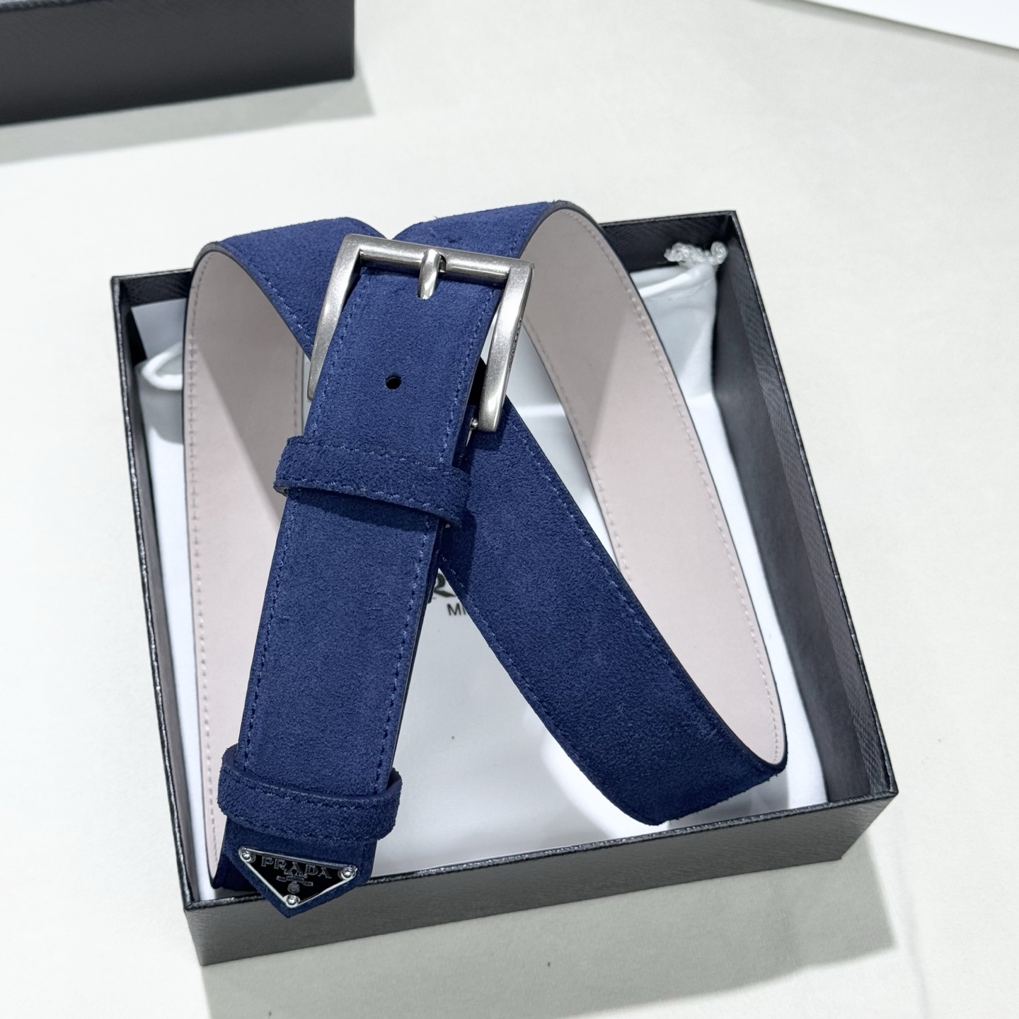 。 男女通用，P rada这款华美的绒面皮革腰带释放简约而精致的优雅气息 尖部的涂珐琅金属三角形徽标展现