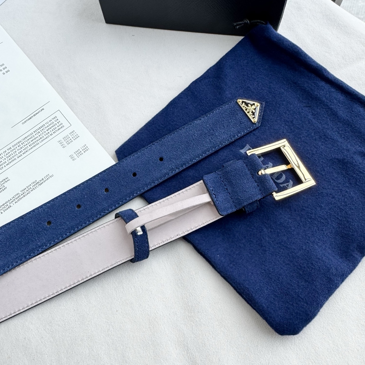 。 男女通用，P rada这款华美的绒面皮革腰带释放简约而精致的优雅气息 尖部的涂珐琅金属三角形徽标展现