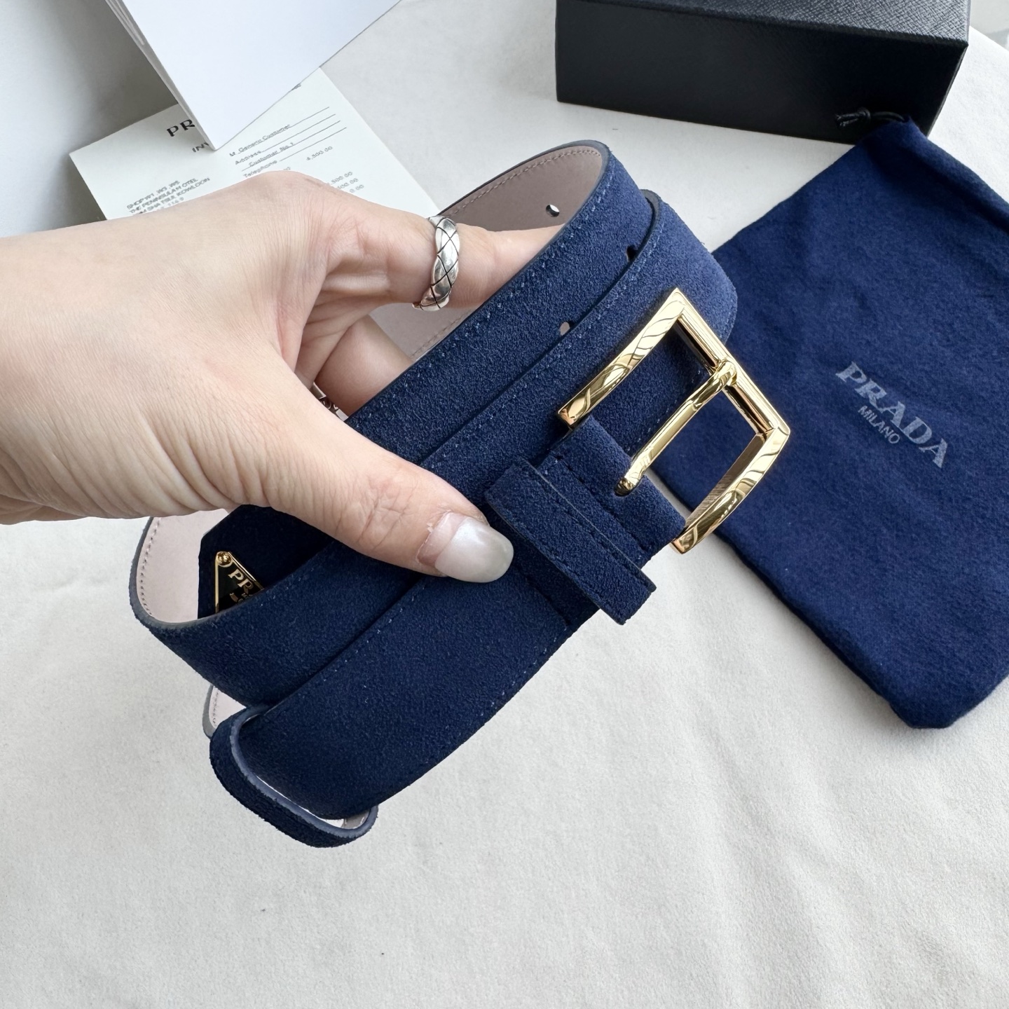 。 男女通用，P rada这款华美的绒面皮革腰带释放简约而精致的优雅气息 尖部的涂珐琅金属三角形徽标展现