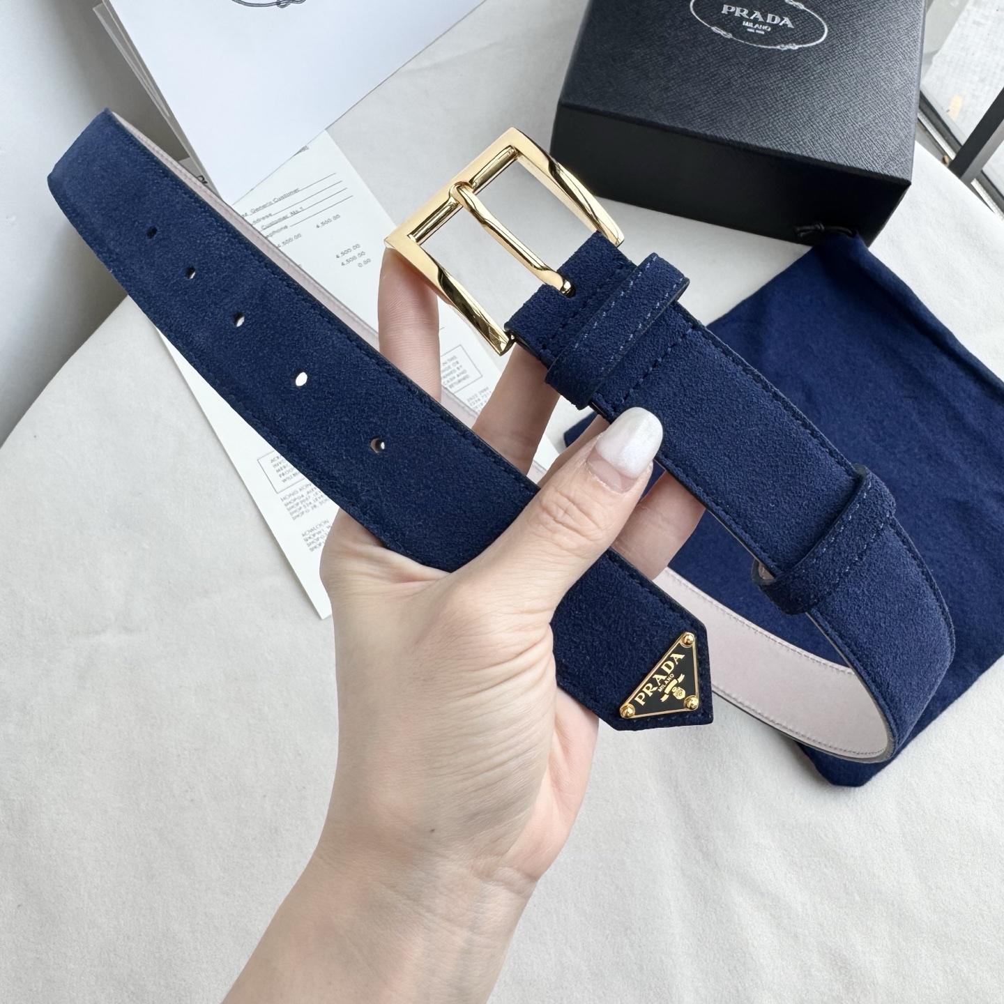 。 男女通用，P rada这款华美的绒面皮革腰带释放简约而精致的优雅气息 尖部的涂珐琅金属三角形徽标展现