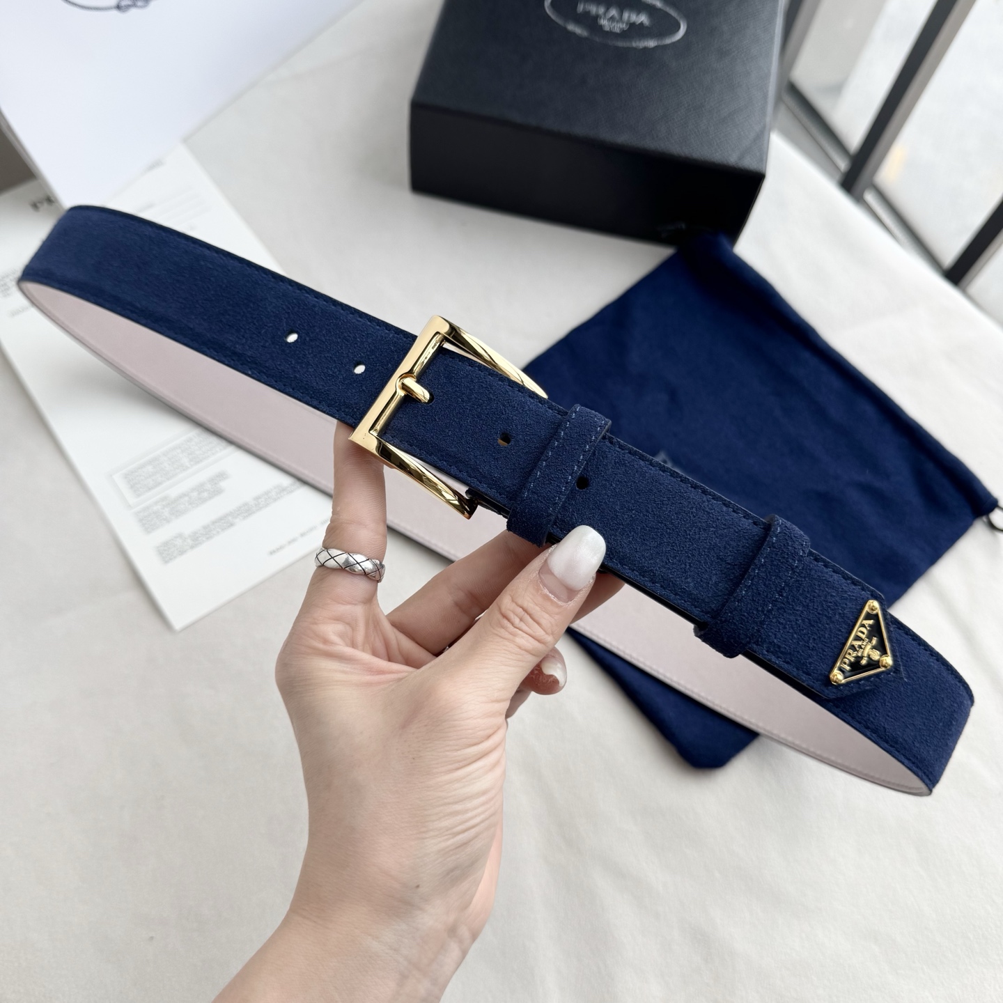 。 男女通用，P rada这款华美的绒面皮革腰带释放简约而精致的优雅气息 尖部的涂珐琅金属三角形徽标展现