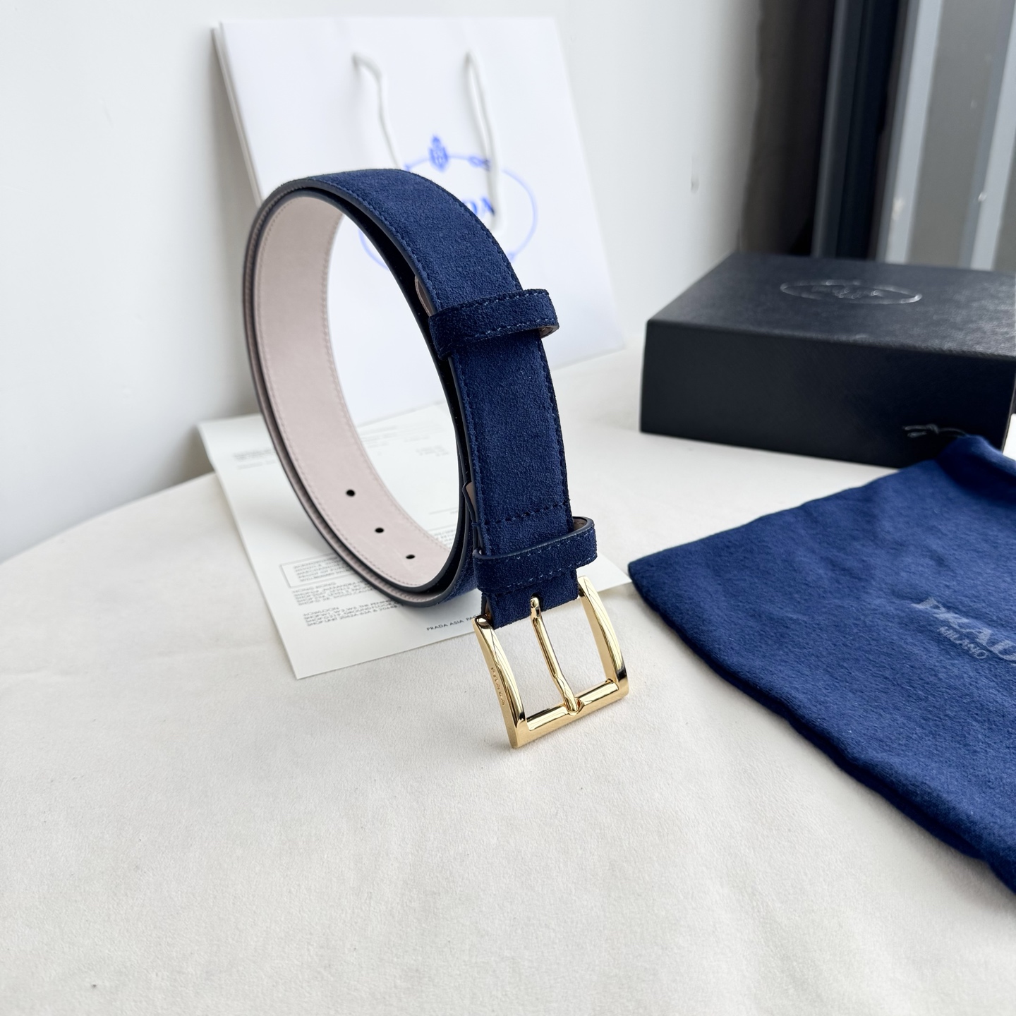 。 男女通用，P rada这款华美的绒面皮革腰带释放简约而精致的优雅气息 尖部的涂珐琅金属三角形徽标展现