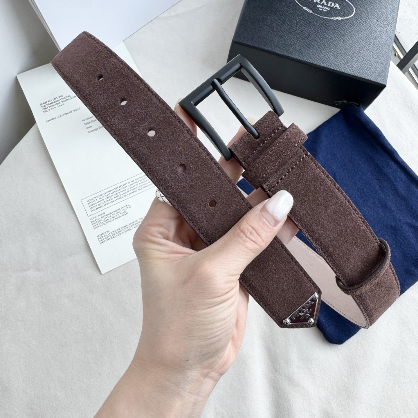 。 男女通用，P rada这款华美的绒面皮革腰带释放简约而精致的优雅气息 尖部的涂珐琅金属三角形徽标展现