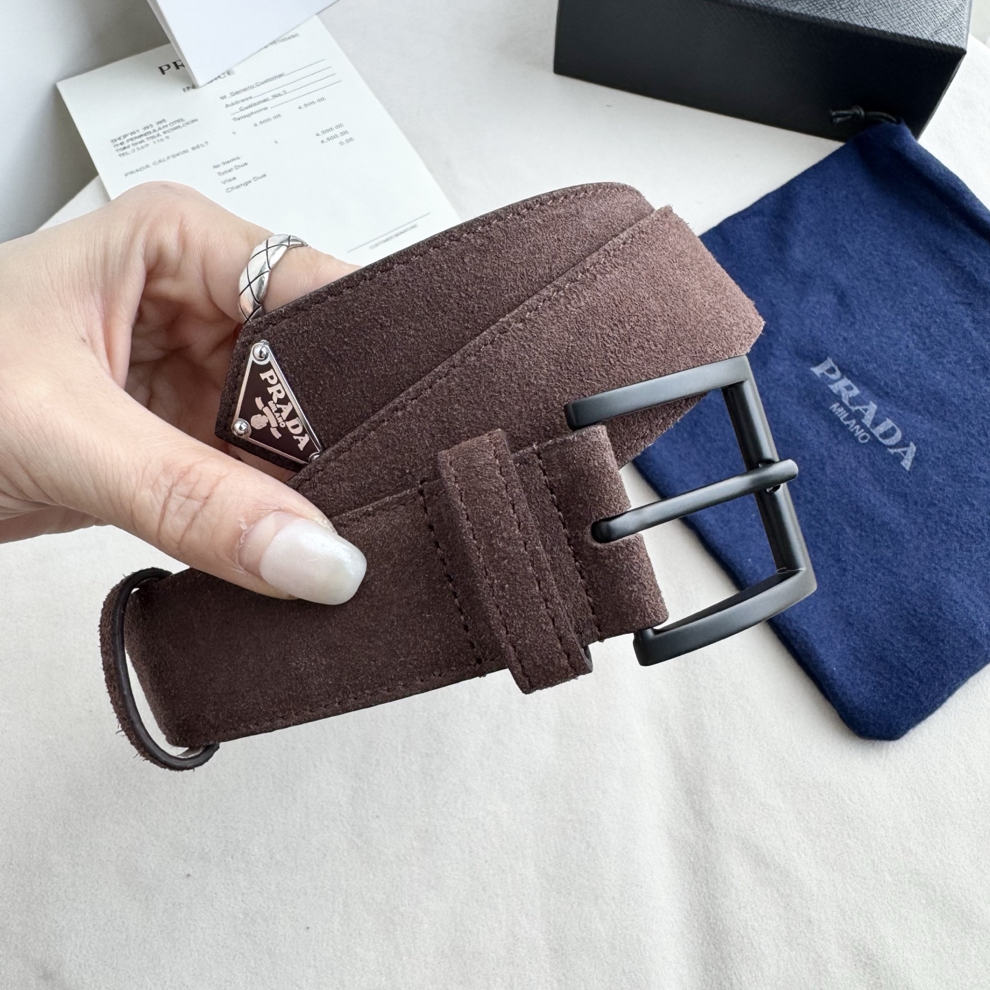 。 男女通用，P rada这款华美的绒面皮革腰带释放简约而精致的优雅气息 尖部的涂珐琅金属三角形徽标展现