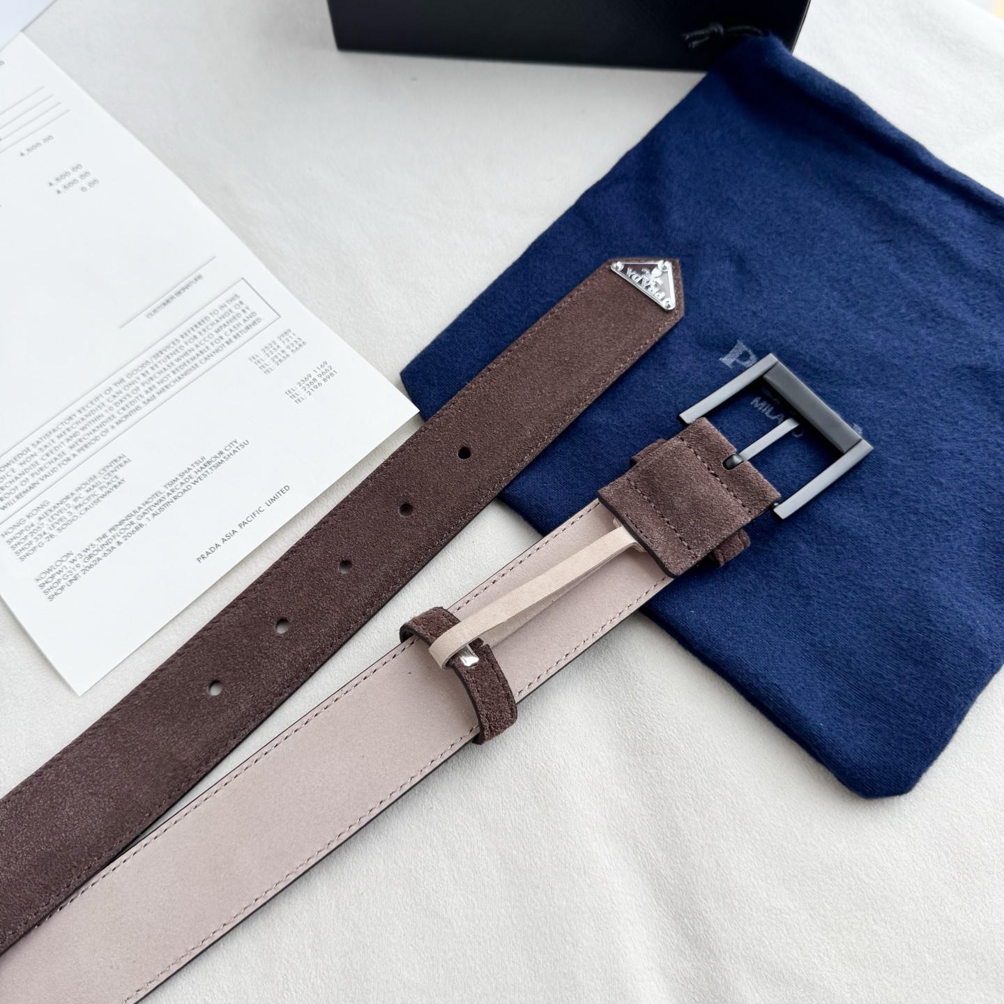 。 男女通用，P rada这款华美的绒面皮革腰带释放简约而精致的优雅气息 尖部的涂珐琅金属三角形徽标展现