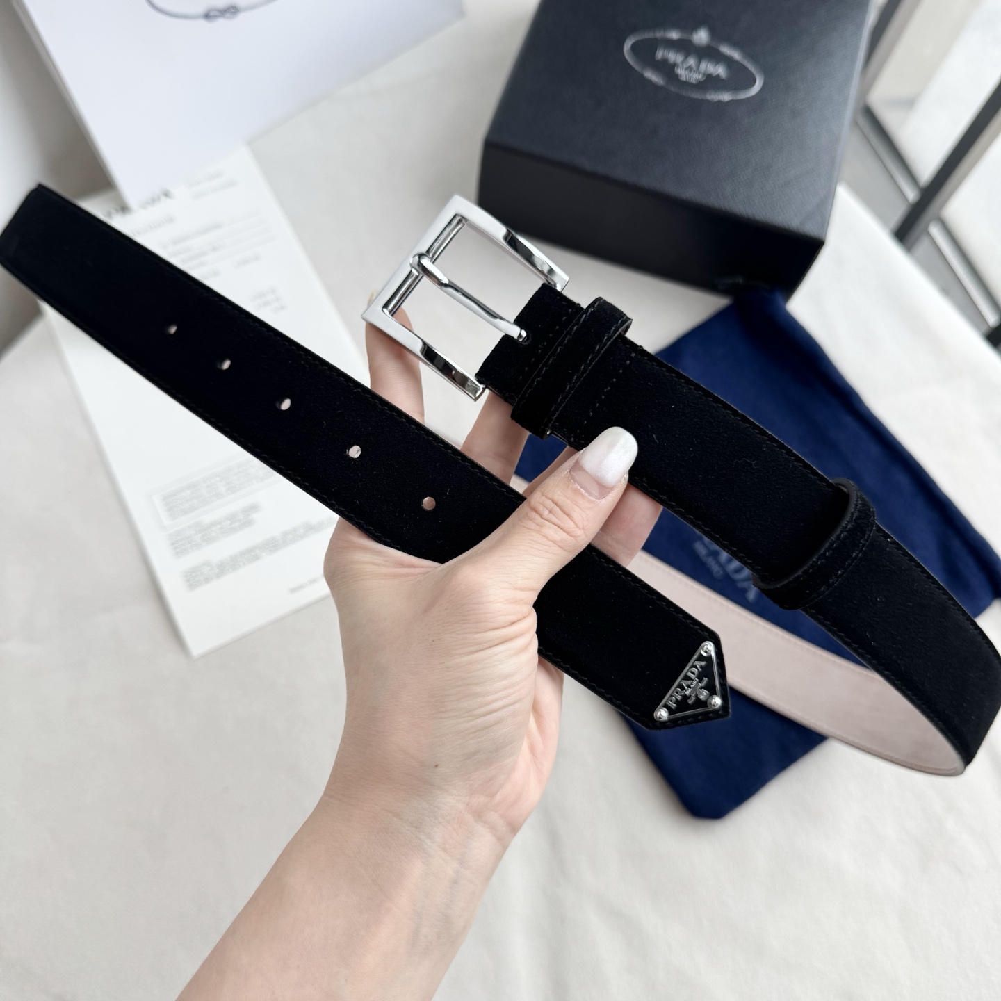 。 男女通用，P rada这款华美的绒面皮革腰带释放简约而精致的优雅气息 尖部的涂珐琅金属三角形徽标展现