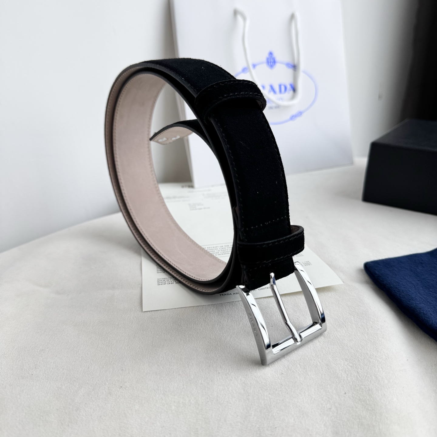 。 男女通用，P rada这款华美的绒面皮革腰带释放简约而精致的优雅气息 尖部的涂珐琅金属三角形徽标展现