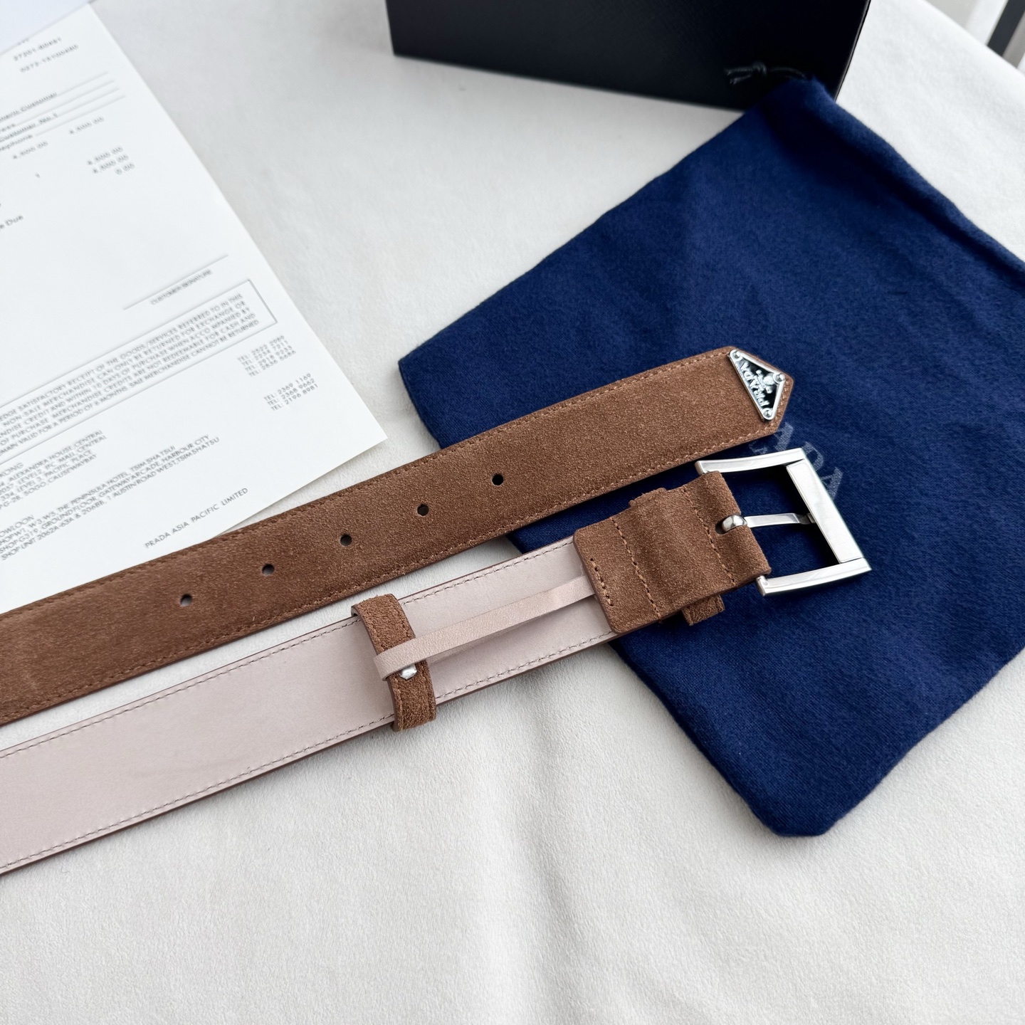。 男女通用，P rada这款华美的绒面皮革腰带释放简约而精致的优雅气息 尖部的涂珐琅金属三角形徽标展现