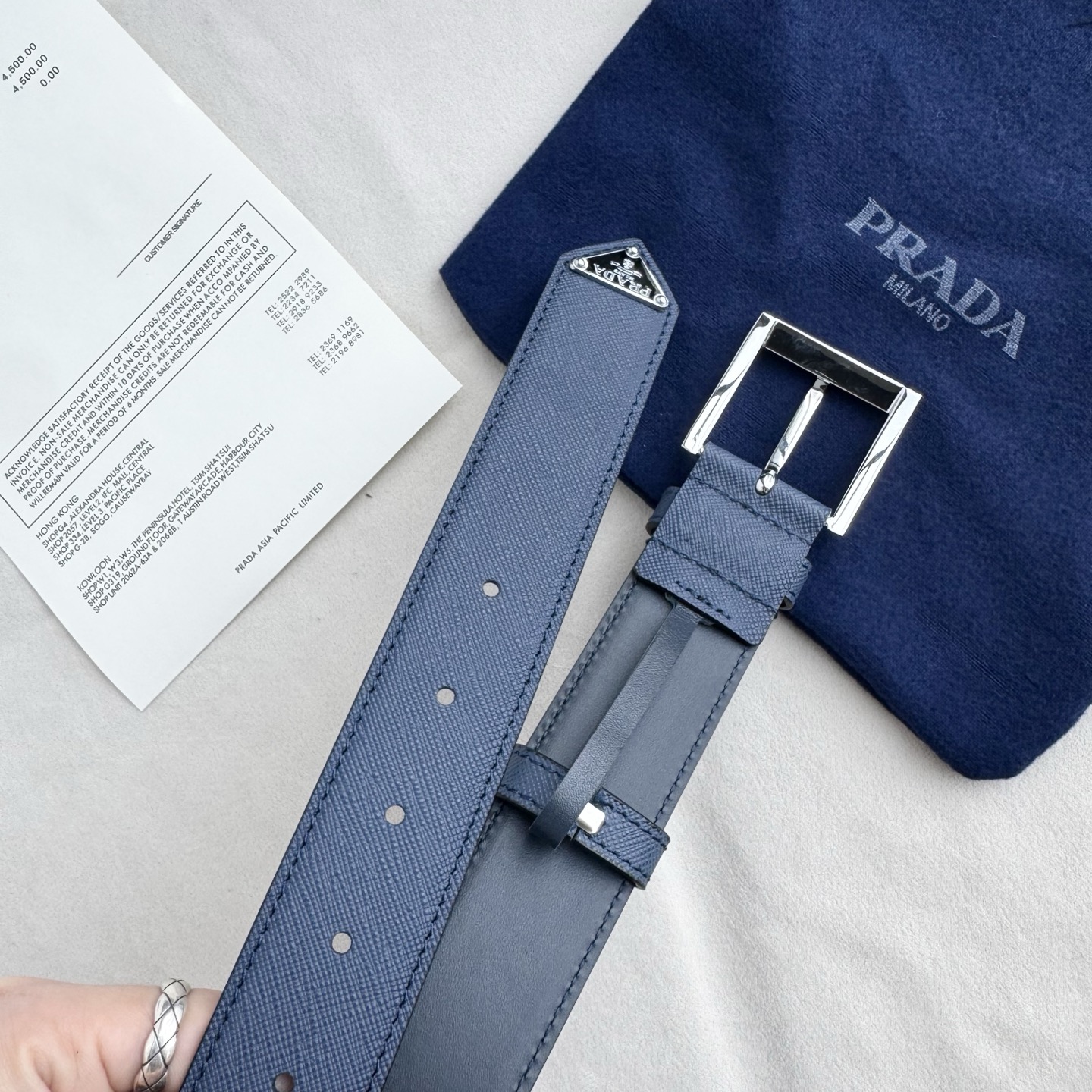 。 男女通用，P rada这款华美的十字纹牛皮腰带释放简约而精致的优雅气息 尖部的涂珐琅金属三角形徽标展