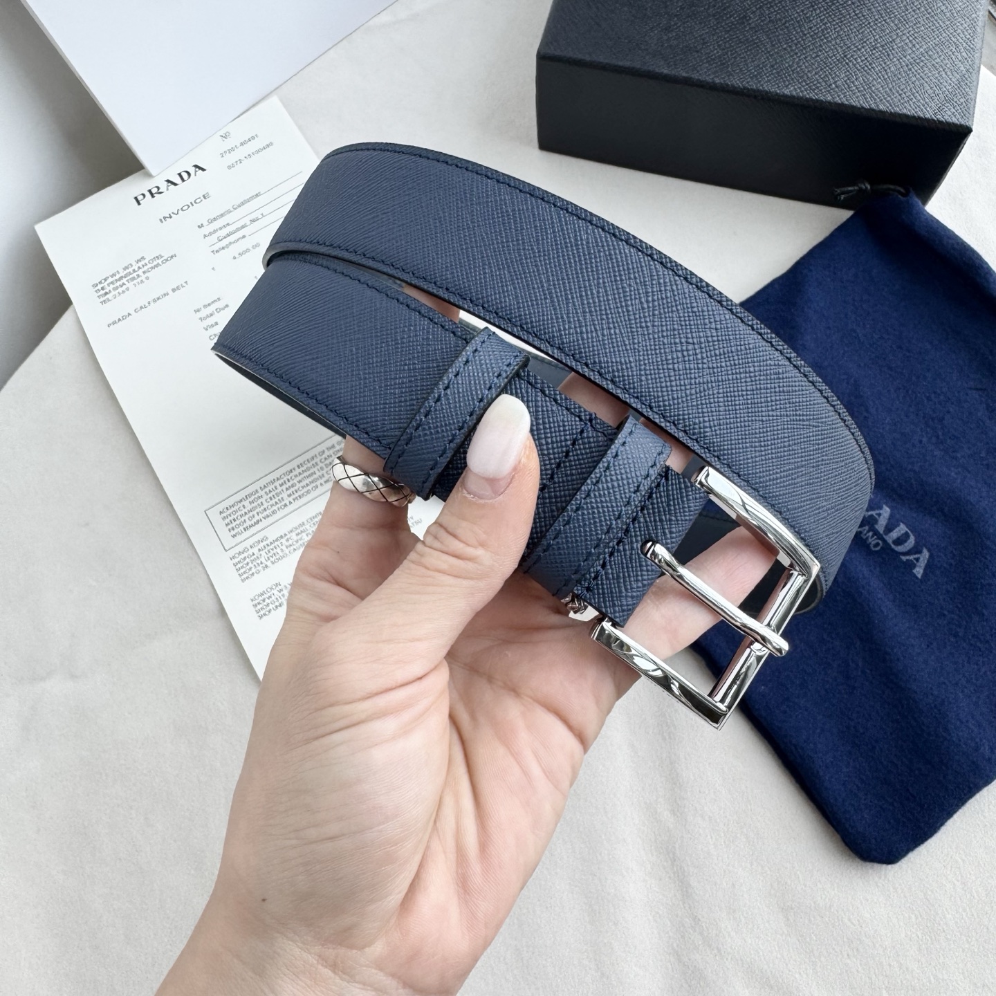 。 男女通用，P rada这款华美的十字纹牛皮腰带释放简约而精致的优雅气息 尖部的涂珐琅金属三角形徽标展