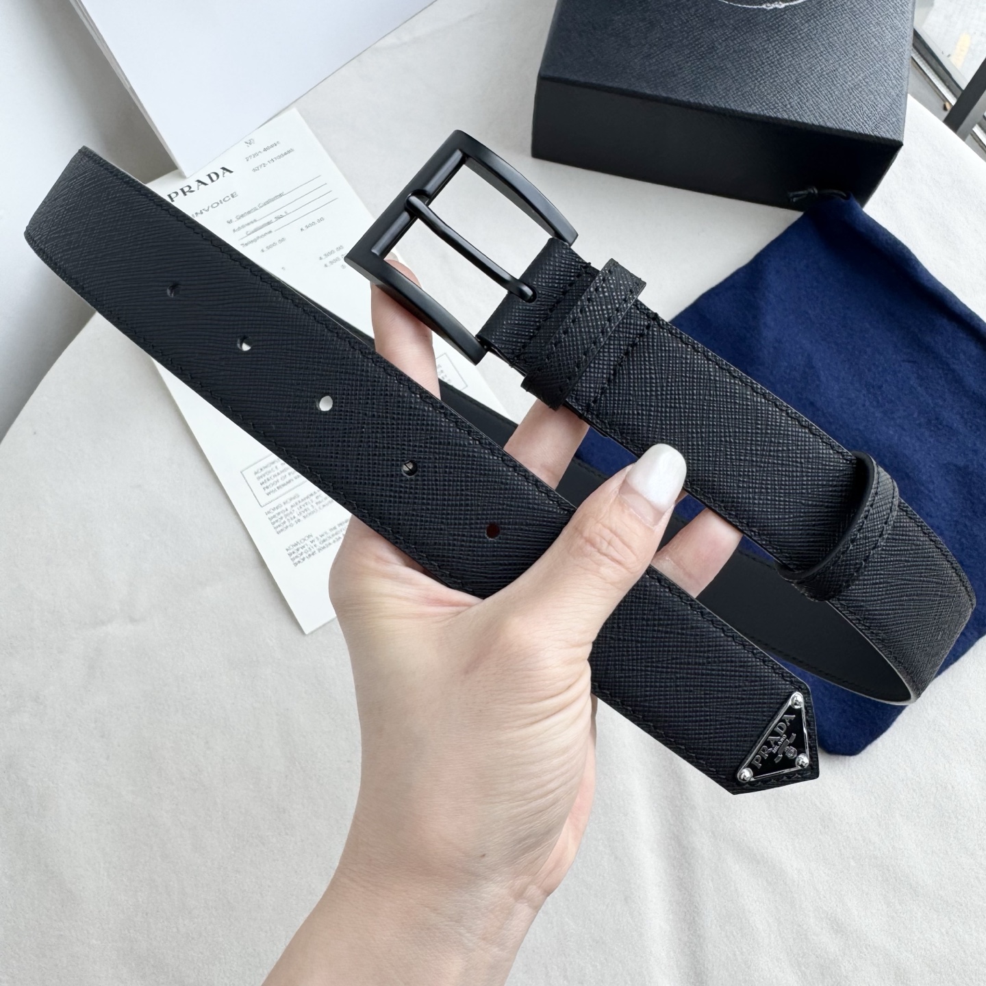 。 男女通用，P rada这款华美的十字纹牛皮腰带释放简约而精致的优雅气息 尖部的涂珐琅金属三角形徽标展
