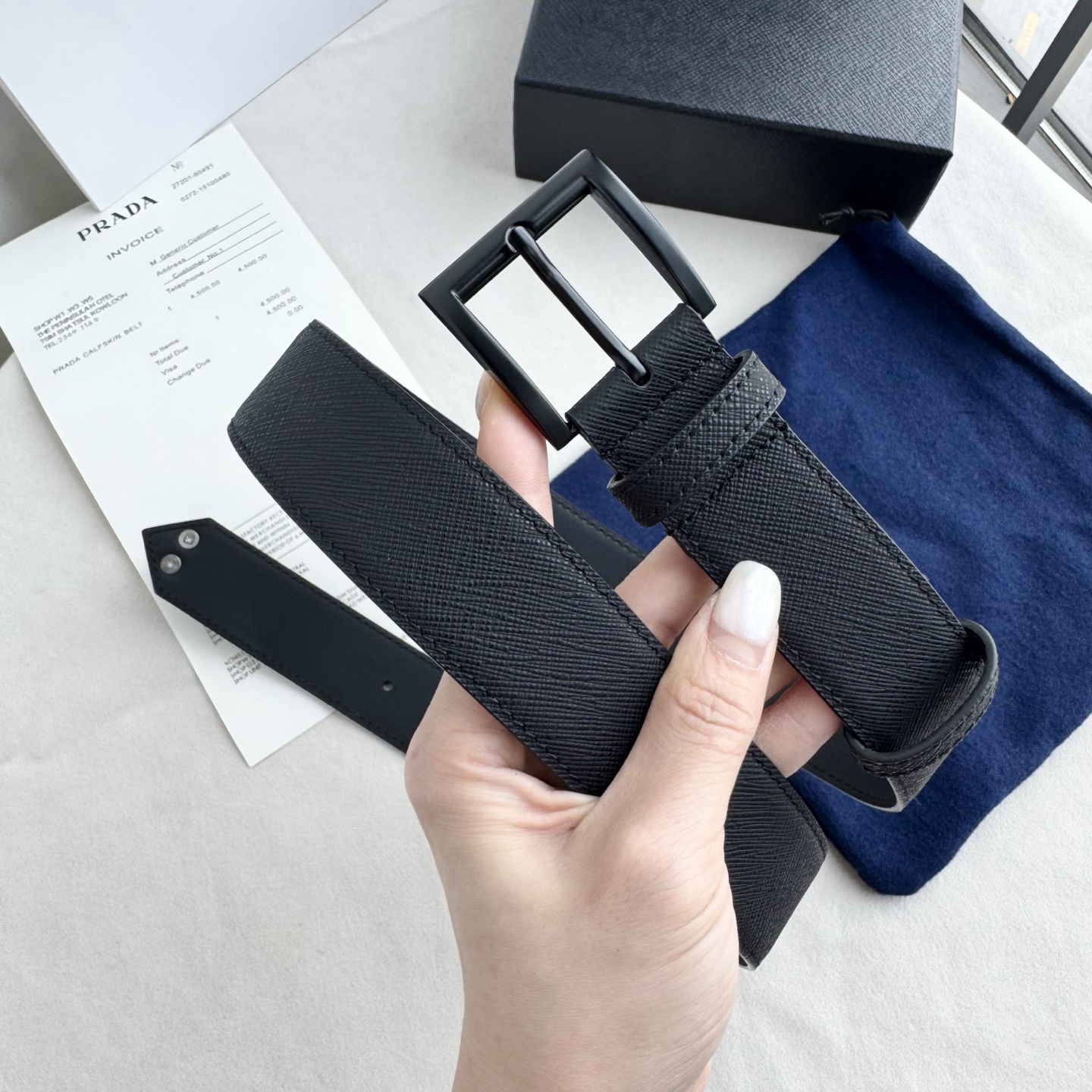 。 男女通用，P rada这款华美的十字纹牛皮腰带释放简约而精致的优雅气息 尖部的涂珐琅金属三角形徽标展