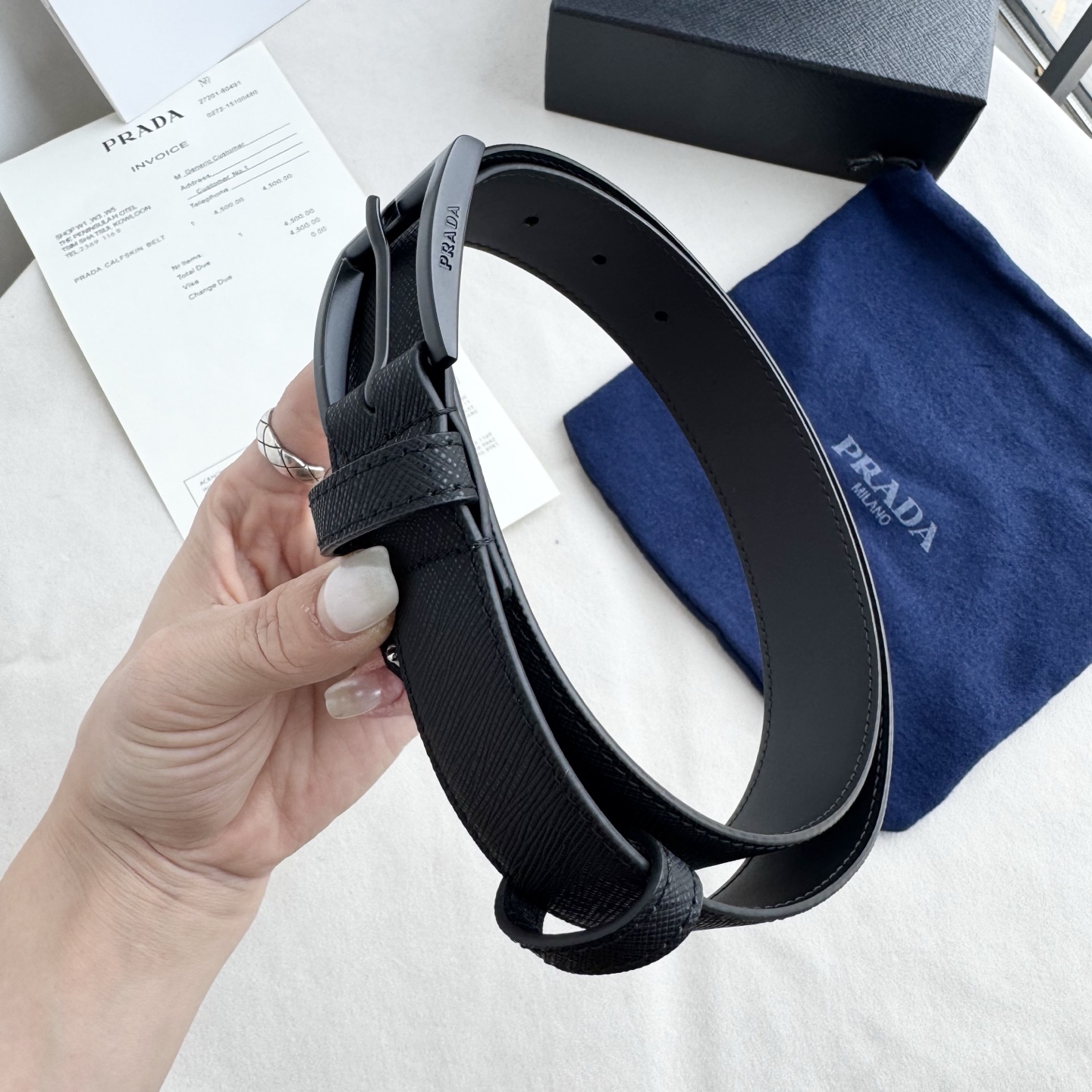 。 男女通用，P rada这款华美的十字纹牛皮腰带释放简约而精致的优雅气息 尖部的涂珐琅金属三角形徽标展