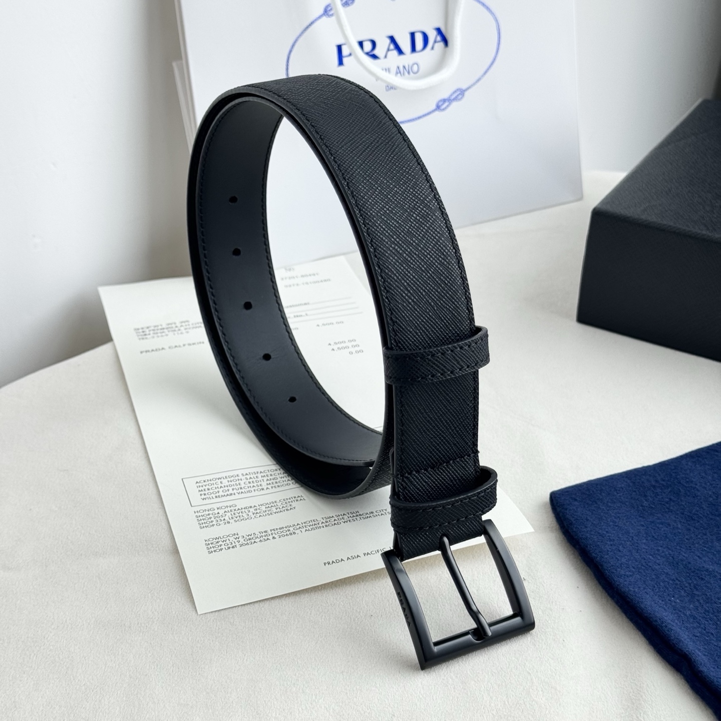 。 男女通用，P rada这款华美的十字纹牛皮腰带释放简约而精致的优雅气息 尖部的涂珐琅金属三角形徽标展