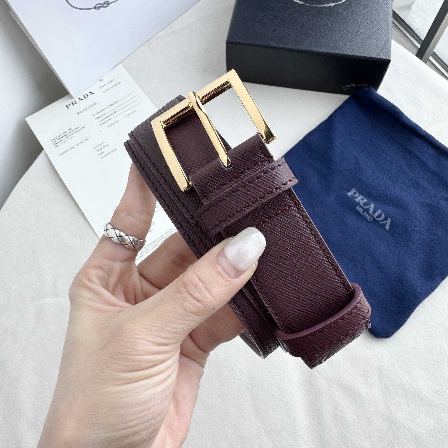 。 男女通用，P rada这款华美的十字纹牛皮腰带释放简约而精致的优雅气息 尖部的涂珐琅金属三角形徽标展