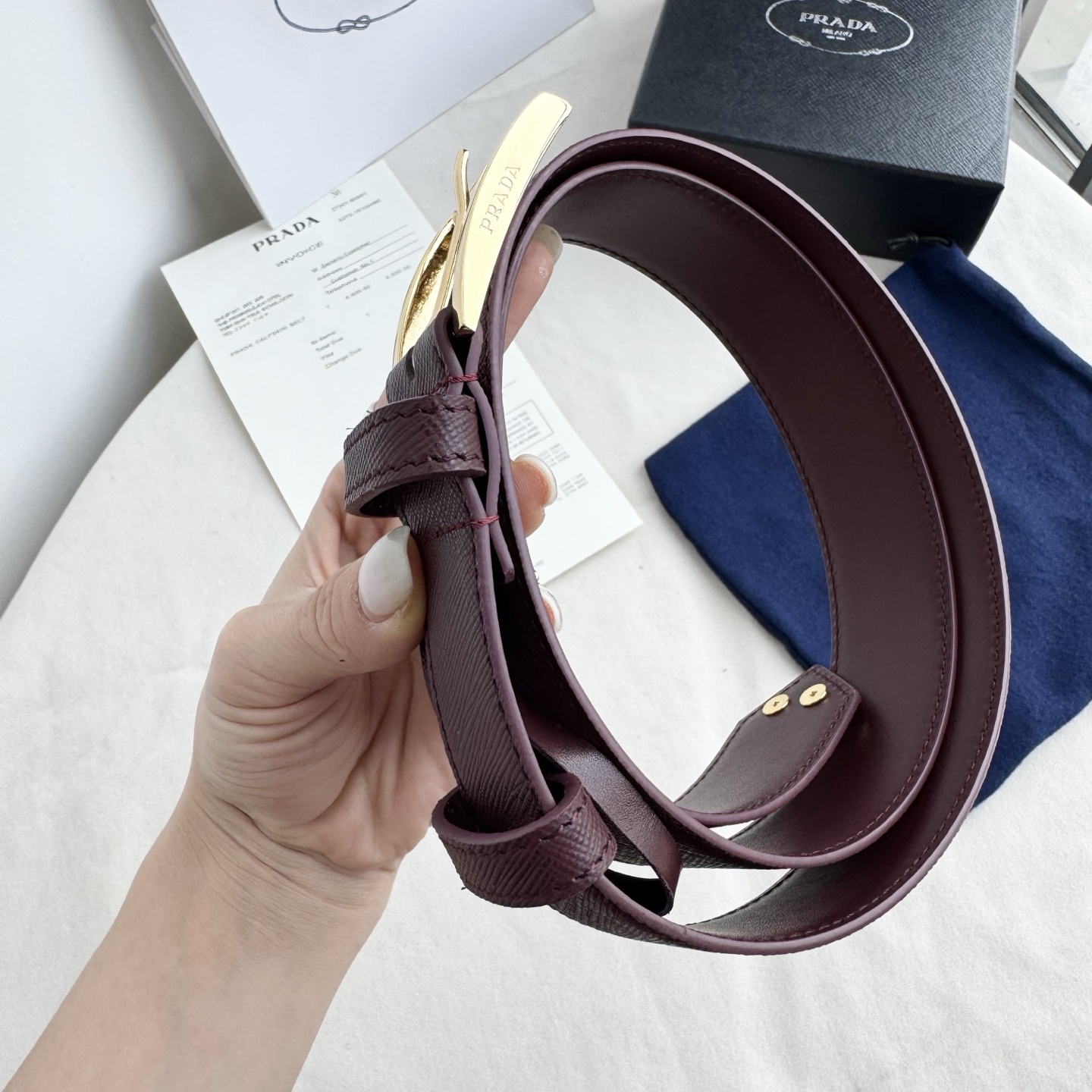 。 男女通用，P rada这款华美的十字纹牛皮腰带释放简约而精致的优雅气息 尖部的涂珐琅金属三角形徽标展