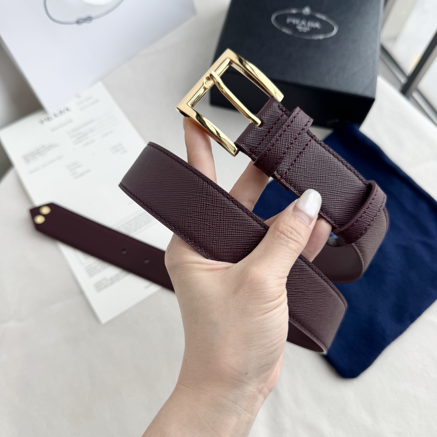 。 男女通用，P rada这款华美的十字纹牛皮腰带释放简约而精致的优雅气息 尖部的涂珐琅金属三角形徽标展