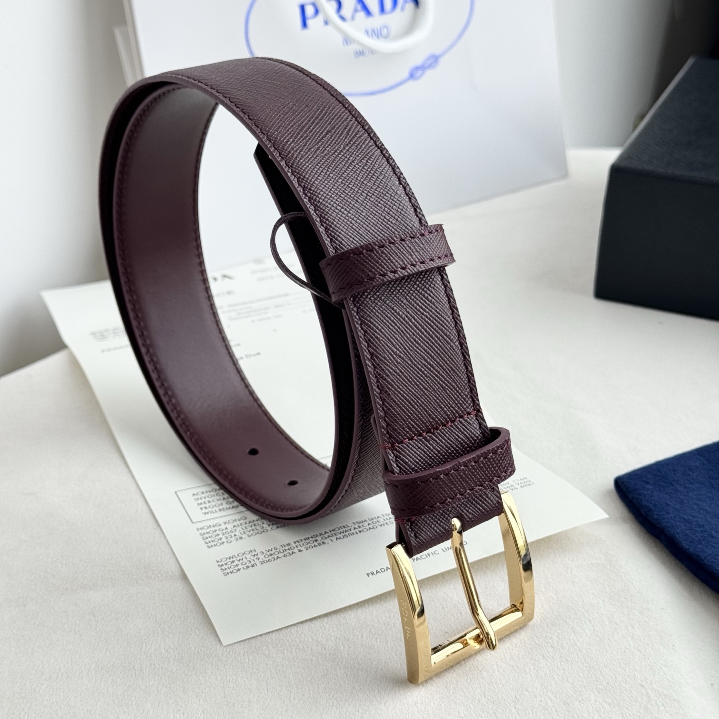 。 男女通用，P rada这款华美的十字纹牛皮腰带释放简约而精致的优雅气息 尖部的涂珐琅金属三角形徽标展