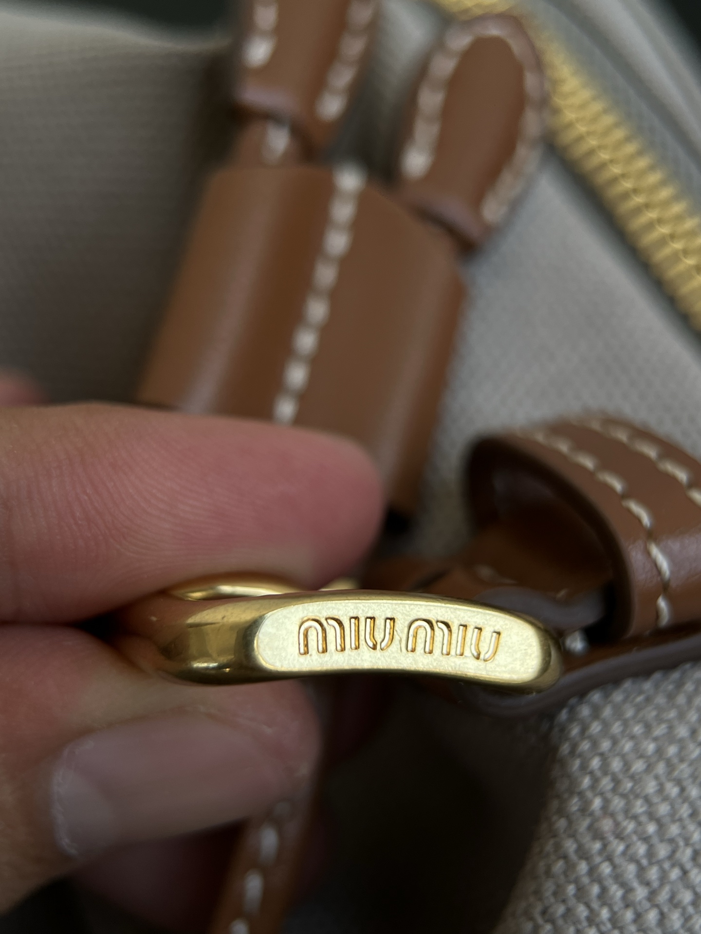 Miu Miu Real shot details of the hardware, made of aged vintage brass. The surface is covered with a layer of old craftsmanship. The lettering is