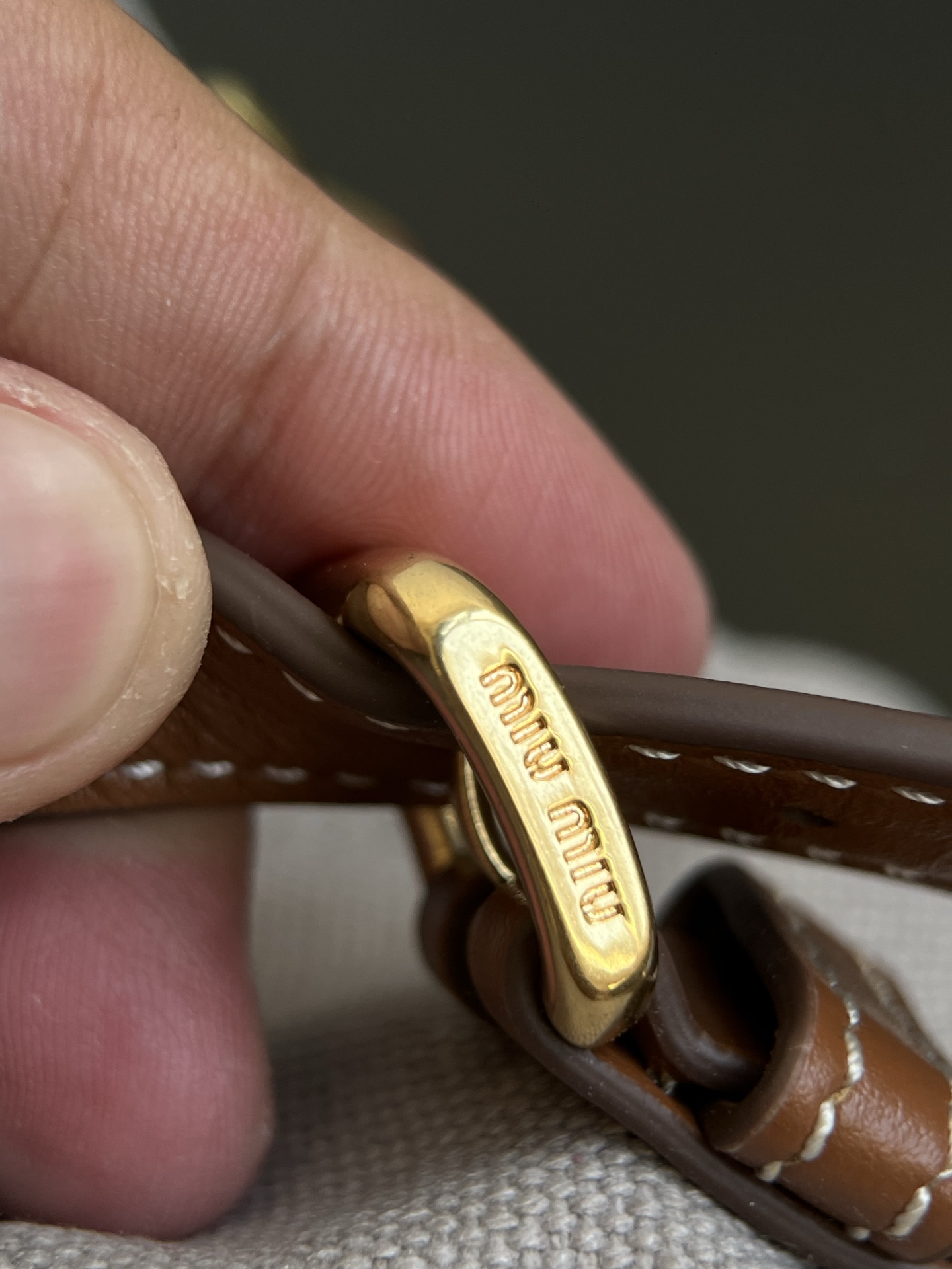 Miu Miu Real shot details of the hardware, made of aged vintage brass. The surface is covered with a layer of old craftsmanship. The lettering is