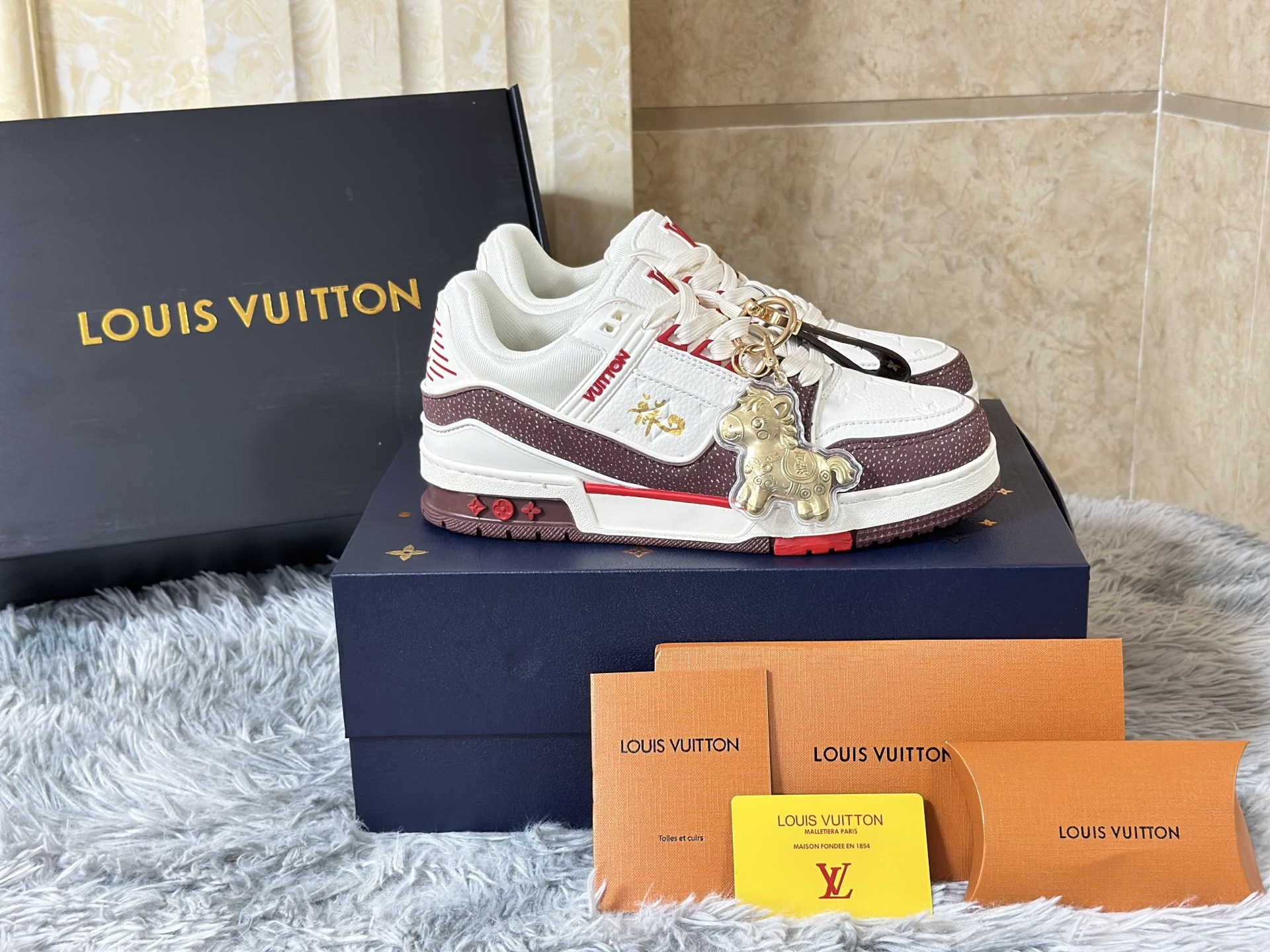 NO:730170,In stock Airplane box version Size 39-45 Men's LOUIS VUITTON 'Year of the Horse Limited' Trainer is a miniature epic dedicated to the zodiac totem by a high-end leather goods workshop. The shoe body is like a mobile collection cabinet, and the main body is made of Box  Calf smooth calfskin carves out the outline of a three-dimensional saddle, and the sides are spliced with Ostrich ostrich leather that has been specially tanned to present a saddle brown gradient color, imitating the flowing texture of horse fur. The iconic Monogram flower is not printed, but covered with laser hollow leather lamination technology on the dark red suede, as if the brand soul is imprinted on the harness.  The inner lining is made of silk printed with the replica pattern of the first LV harness order in 1896, and the inside of the tongue is hand-painted with a miniature gold foil horse head badge. The midsole is not ordinary rubber, but a composite material injected with metal powder, which is polished to give a warm luster like bronze. The outsole pattern is made of traditional horseshoe forging patterns intertwined with LV diamond patterns.  It transcends the general categories of sports shoes or luxury goods and has become a triple totem that connects the centuries-old saddlery family tradition, zodiac culture and contemporary street aesthetics - every time you wear it, you are completing a journey across time.,, louis vuitton, louis vuitton, sneakers, cowhide, ostrich skin, chamois leather19860909现货 飞机盒版本 尺码39-45 男款 LOUIS VUITTON “马年限定” Trainer,是高级皮具工坊献给生肖图腾的一首微缩史诗. 鞋身如一座移动的典藏柜,主体采用Box Calf光面小牛皮雕琢出立体鞍具轮廓,侧面拼接经特殊鞣制呈现马鞍棕渐变色的Ostrich鸵鸟皮,模仿骏马皮毛的流光质感.标志性的Monogram花卉并非印花,而是以激光镂空皮革层压技术覆盖于深红色麂皮之上,如同将品牌灵魂烙刻于马具. 内衬选用印有1896年首份LV马具订单复刻图案的丝绸,鞋舌内侧则手绘微型金箔马首徽章.中底并非普通橡胶,而是注入金属粉末的复合材质,经抛光呈现青铜器般的温润光泽,外底纹路由传统马蹄铁锻造纹路与LV菱形格交织而成. 它超越了运动鞋或奢侈品的一般范畴,成为连接百年马具世家传统、生肖文化与当代街头美学的三重图腾——每一次穿着,皆是在完成一场跨越时间的巡礼.,,louis vuitton,louis vuitton,sneakers,cowhide,ostrich skin,chamois leather,Men's shoes