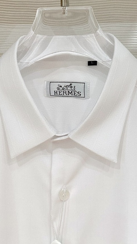 爱马仕（Hermès）高端面料和低调奢华的设计著称。左胸橙色Caleche（凯来诗/马车）刺绣，是爱马仕