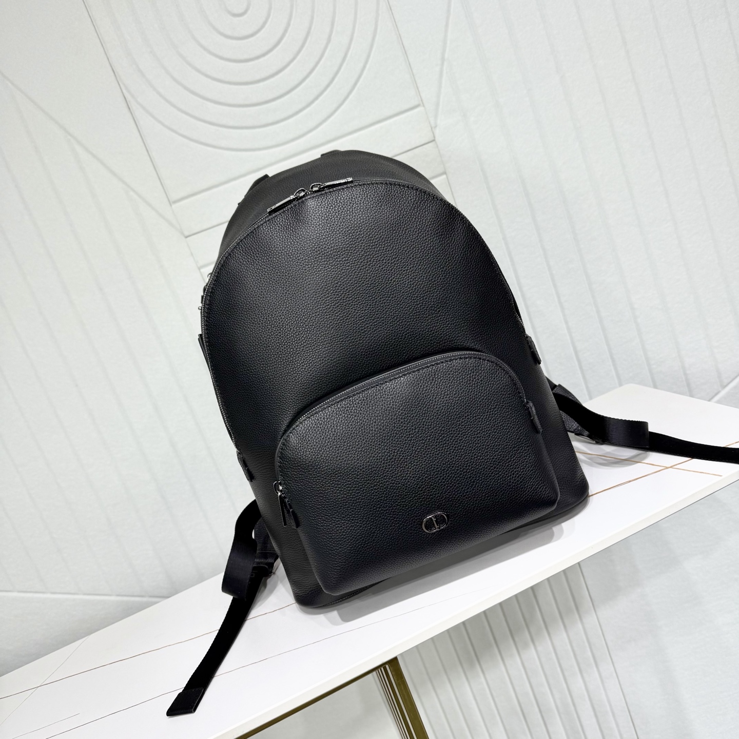 780💰市场最高版本（原单品质）正品打版

【保证全头层进口牛皮，拒绝二层皮，拒绝超纤皮】

CD Icon 拉链双肩背包
黑色哑光粒面牛皮革
编号: 1ICBA233ICO_H00N
这款 CD Icon 拉链是二零二五冬季系列新品，简约设计，彰显 Dior 精湛工艺。采用黑色哑光粒面牛皮革精心制作，正面饰以黑色金属覆层 CD Icon 标志，搭配悬挂在 D 形饰环上的皮革行李标牌，点缀以 CD 压花标志提升格调。宽大的拉链隔层设有两个插袋和一个拉链口袋，CD 里料灵感源自 Dior 的精裁工艺。款式经典，搭配可折叠顶部手柄和可调节、可拆卸的肩带，可手提、肩背或斜挎，与各式单品相得益彰。
主体：牛皮革
里料：科技面料，棉，牛皮革
拉链主隔层
2 个插袋和 1 个内部拉链口袋
D 形饰环可悬挂 CD 压花皮革行李标牌
顶部皮革手柄
可调节、可拆卸的皮革肩带搭配龙虾扣和肩垫
后侧拉杆饰带
正面黑色金属覆层铜合金 CD Icon 标志
内部饰有 Dior 压花标志
内含防尘袋
意大利制造
尺寸：31 x 40 x 19 厘米（长 x 高 x 宽）
主隔层可收纳 1 部 15 英寸笔记本、A4 文件和 1 部平板