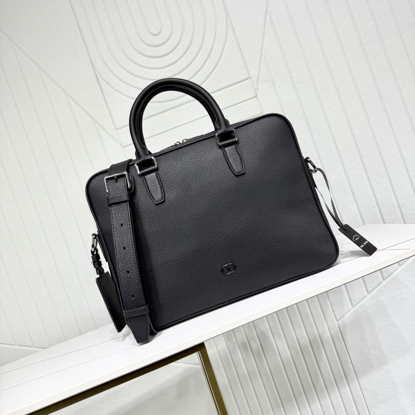 780💰市场最高版本（原单品质）正品打版

【保证全头层进口牛皮，拒绝二层皮，拒绝超纤皮】

CD Icon 拉链公文包
黑色哑光粒面牛皮革
编号：1ICBR184ICO_H00N
这款 CD Icon 拉链是二零二五冬季系列新品，简约设计，彰显 Dior 精湛工艺。采用黑色哑光粒面牛皮革精心制作，正面饰以黑色金属覆层 CD Icon 标志，搭配悬挂在 D 形饰环上的皮革行李标牌，点缀以 CD 压花标志提升格调。宽大的拉链隔层设有两个插袋和一个拉链口袋，CD 里料灵感源自 Dior 的精裁工艺。款式经典，搭配可折叠顶部手柄和可调节、可拆卸的肩带，可手提、肩背或斜挎，与各式单品相得益彰。
主体：牛皮革
里料：科技面料，棉，牛皮革
拉链主隔层
2 个插袋和 1 个内部拉链口袋
D 形饰环可悬挂 CD 压花皮革行李标牌
顶部皮革手柄
可调节、可拆卸的皮革肩带搭配龙虾扣和肩垫
后侧拉杆饰带
正面黑色金属覆层铜合金 CD Icon 标志
内部饰有 Dior 压花标志
内含防尘袋
意大利制造     
尺寸：36 x 27.5 x 5.5 厘米（长 x 高 x 宽）
主隔层可收纳 1 部 13 英寸笔记本、A4 文件和 1 部平板