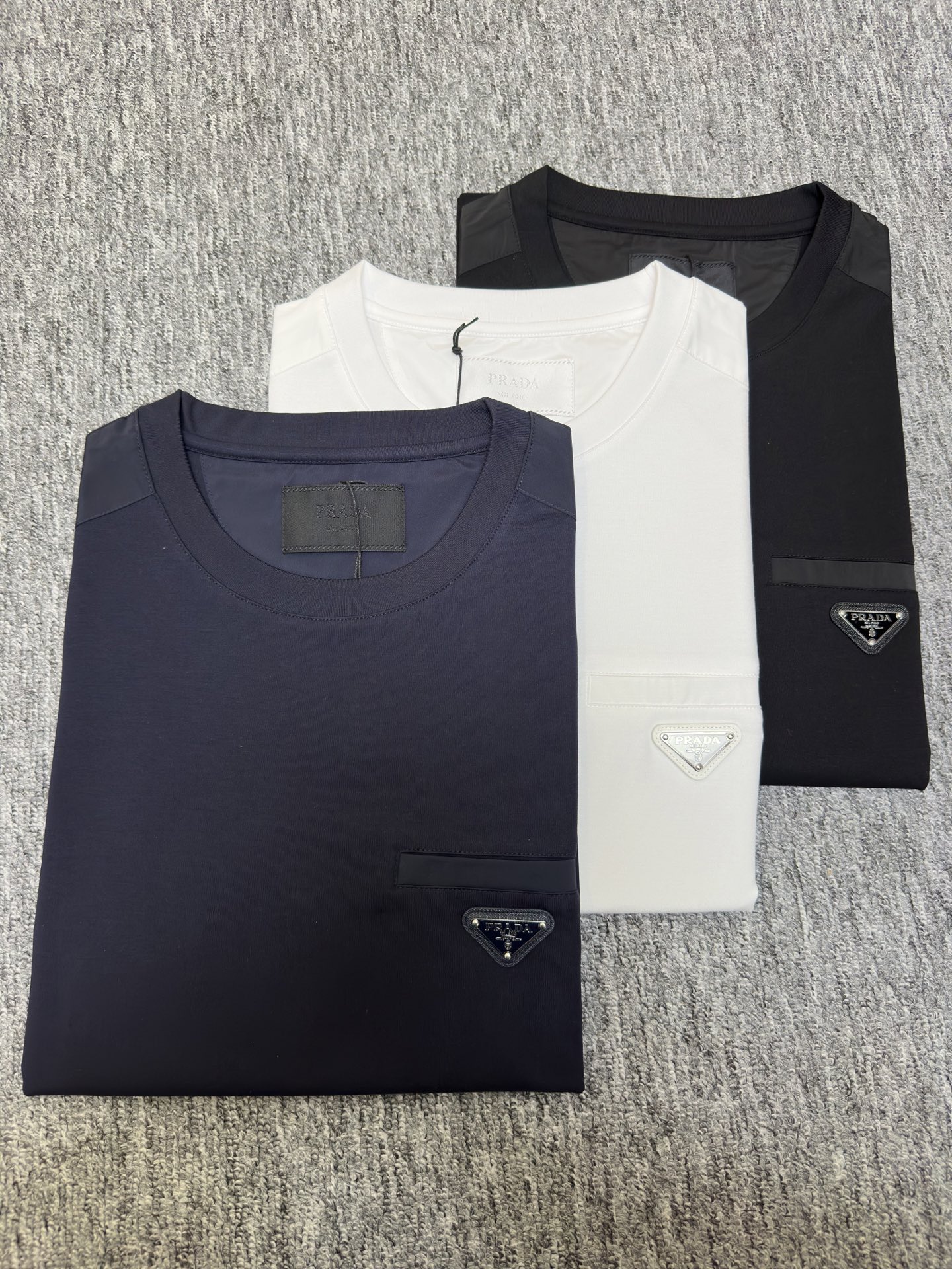 Prada26春夏新品液氨T恤 Prada这款基础款T恤秉承品牌低调简约的理念，经典的针梭织拼接设计，肩