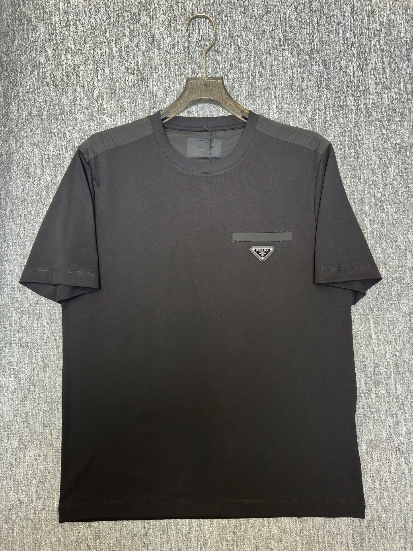 Prada26春夏新品液氨T恤 Prada这款基础款T恤秉承品牌低调简约的理念，经典的针梭织拼接设计，肩