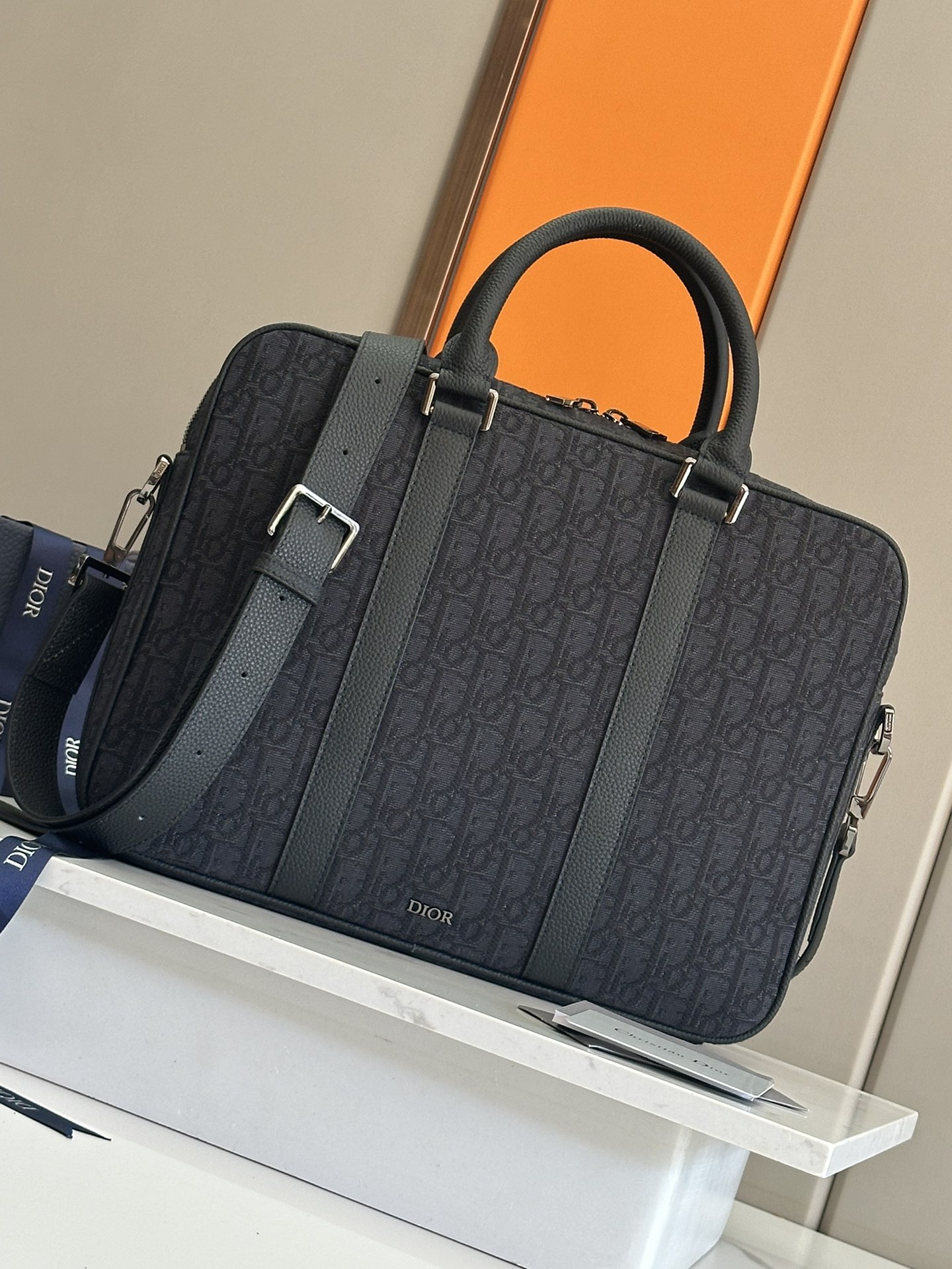 NO:395069,48 This briefcase is a new product for men's fall 2024. It combines classic elegance with the high-order spirit of Dior. Rigid style, carefully crafted in black CD Diamond pattern canvas. The CD Diamond pattern designed by Marc Bohan in 1974 reinterprets the CD first letter in three-dimensional line diamond pattern, presented on cotton canvas. Tonal grained cowhide leather details and front Dior logo enhance the style, zippered and closure, with spacious internal laptop compartment. Paired with foldable handles and adjustable and removable shoulder straps, it can be carried, shoulder or crossbody. Nylon interior Zipper main compartment Internal laptop flat compartment 2 internal plugs Leather top handle  Adjustable, removable leather shoulder strap with lobster buckle Metal clad brass Dior logo on the front Dior embossed logo on the inside Dust bag included Made in Italy Dimensions 37 x 28 x 6 cm (L x H x W) Main compartment can hold 1 13-inch laptop, 1 tablet and A4 file No.: 1ESBRCD Black cloth, Dior, dior, dior, cowhide1986090948 这款公文包是二零二四秋季男装系列新品,将经典优雅与 Dior 的高订精神融为一体.刚性款式,采用黑色 CD Diamond 图案帆布精心制作.马克·博昂 (Marc Bohan) 于 1974 年设计的 CD Diamond 图案以立体线条菱形图案重新诠释 CD 首字母,呈现于棉质帆布上.同色调粒面牛皮革细节与正面 Dior 标志提升格调,拉链开合,设有宽敞的内部笔记本电脑隔层.搭配可折叠手柄和可调节、可拆卸的肩带,可手提、肩背或斜挎. 尼龙内部 拉链主隔层 内部笔记本电脑扁平隔层 2 个内部插袋 皮革顶部手柄 可调节、可拆卸的皮革肩带搭配龙虾扣 正面金属覆层黄铜 Dior 标志 内侧饰有 Dior 压花标志 内含防尘袋 意大利制造 尺寸37 x 28 x 6 厘米（长 x 高 x 宽） 主隔层可收纳 1 台 13 英寸笔记本电脑、1 台平板电脑和 A4 文件 编号: 1ESBRCD 黑色布,迪奥,dior,dior,cowhide,Bag