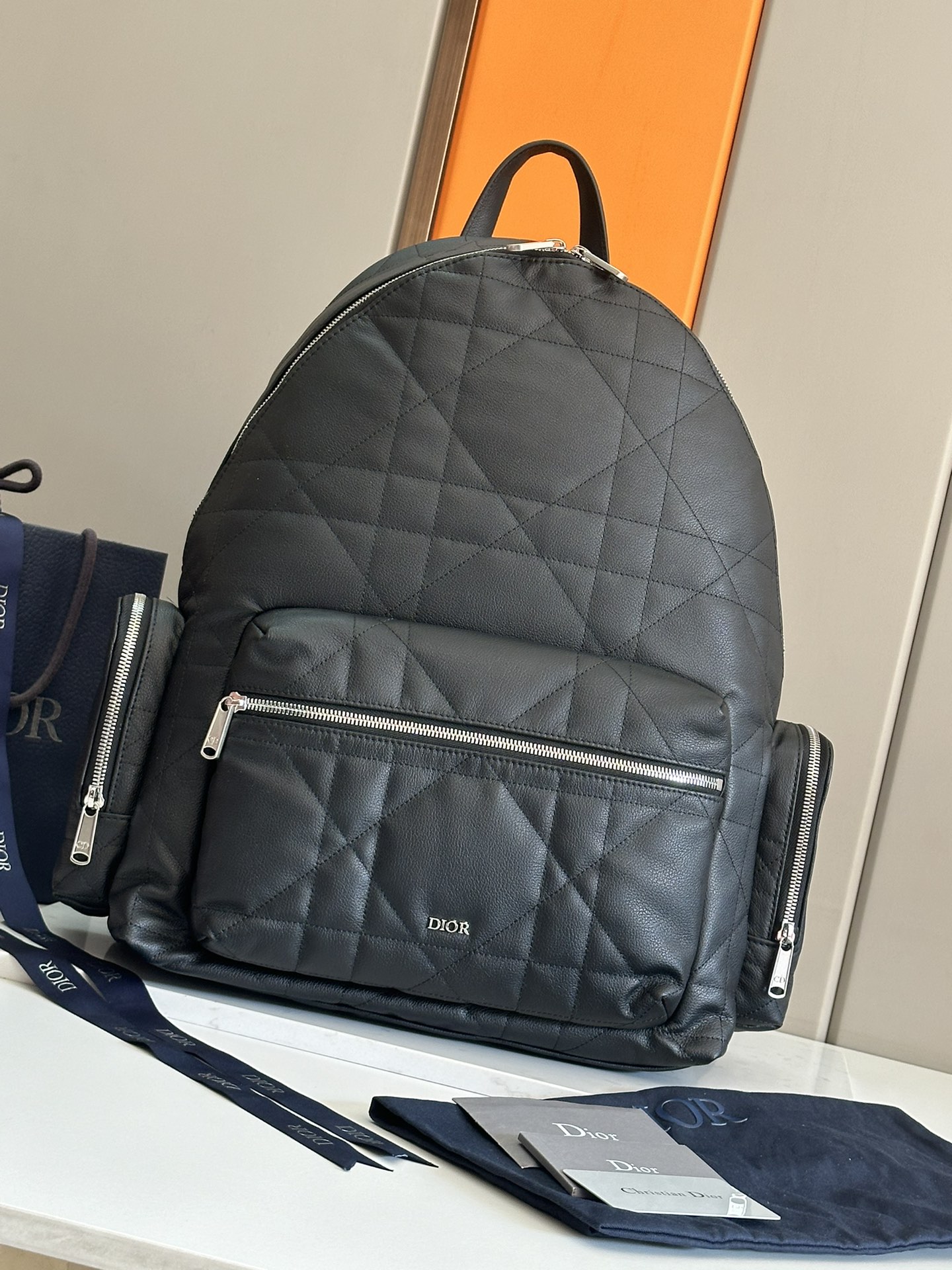 NO:395038,This backpack is a new product in the 2024 winter men's clothing series. It combines modern style with high-order spirit and is eye-catching and fashionable. It is carefully crafted from black cowhide leather and is decorated with larger rattan plaid patterns to rejuvenate the classic Dior pattern, and is matched with the front Dior logo to enhance the style. It has a spacious zipper compartment that can accommodate a variety of daily necessities. The front and side zipper pockets can store wallets, keys, headphones or mobile phones for easy access. Practical and versatile, it is the finishing touch of various shapes. Body cowhide, fabric, lining fabric, cowhide leather Zipper main compartment Internal flat computer compartment Front zipper pocket Two side zipper pockets Leather top handle Adjustable padded shoulder straps Back with padded mesh fabric adorned with Dior logo The front is decorated with retro silver finish brass  Dior logo Interior is decorated with Dior embossed logo Dimensions 41.5 x 46 x 22 cm Number: 1ESBA220MNE_H00N, Dior, dior, dior, wallets, backpacks, cowhide19860909这款双肩背包是二零二四冬季男装系列新品,将现代风格与高订精神融为一体,醒目时尚.采用黑色牛皮革等材质精心制作,饰以加大藤格纹图案,焕新演绎 Dior 经典图案,搭配正面 Dior 标志提升格调.设有一个宽敞的拉链隔层,可收纳各种日常用品,正面口袋和侧面拉链口袋可收纳钱包、钥匙、耳机或手机,便于轻松取用.实用百搭,是各式造型的点睛之笔. 主体牛皮革,织物 里料织物,牛皮革 拉链主隔层 内部扁平电脑隔层 正面拉链口袋 两个侧面拉链口袋 皮革顶部手柄 可调节加垫肩带 背部采用加垫网眼织物,饰以 Dior 标志 正面饰以复古银色饰面黄铜 Dior 标志 内部饰有 Dior 压花标志 尺寸41.5 x 46 x 22 厘米 编号: 1ESBA220MNE_H00N,迪奥,dior,dior,wallets,backpacks,cowhide,Bag