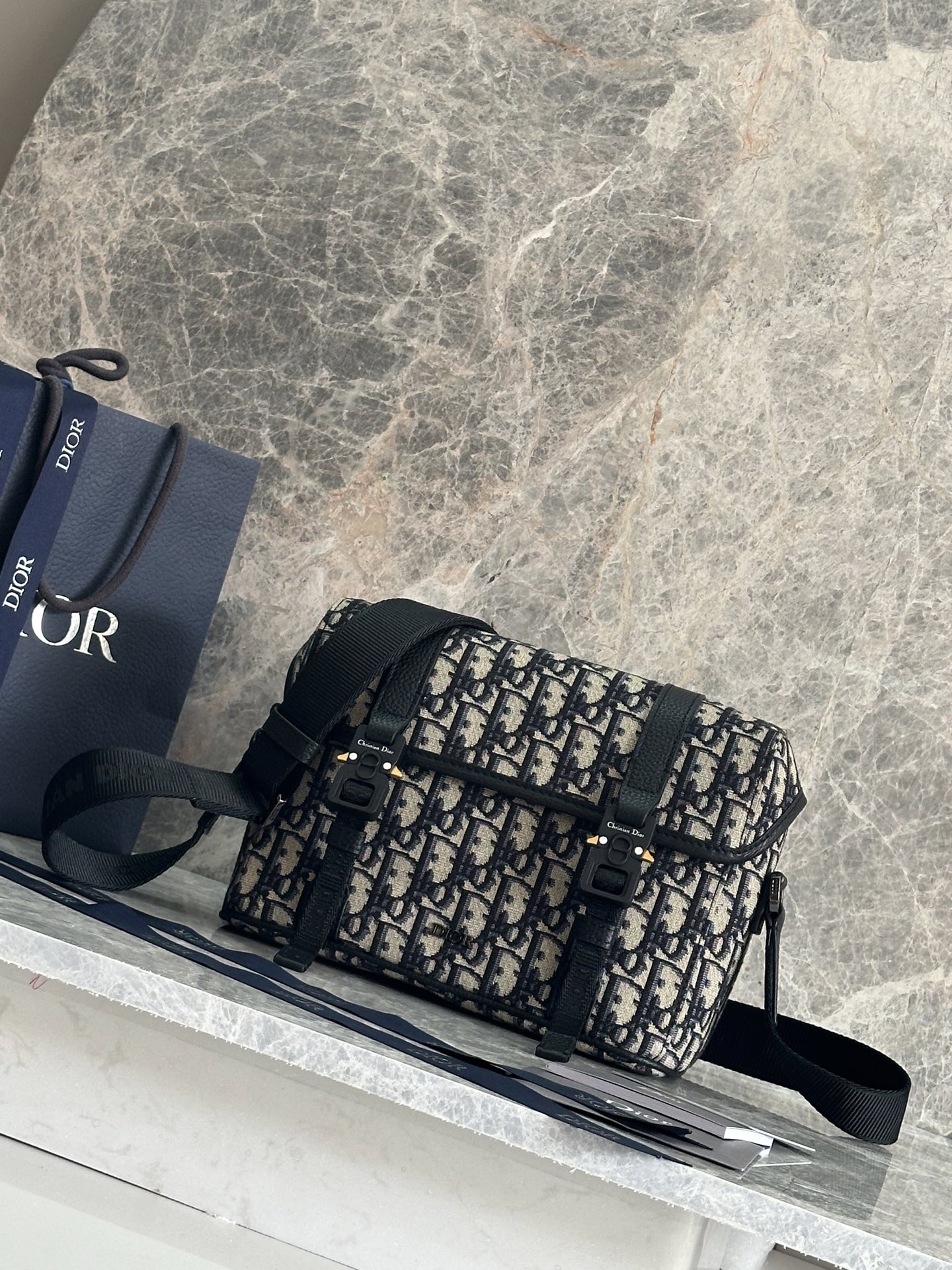 NO:395165,P This messenger bag is paired with a flap, and the modern and fashionable design fully highlights the high-order spirit of Dior, further enriching the Dior Hit The Road series. The Dior Gravity printed leather uses embossing technology to present classic patterns on black cowhides, highlighting the exquisite craftsmanship of Dior Workshop. The flip is paired with CD logo mini aluminum buckles and two Christian Dior nylon jacquard strips. The spacious compartment can accommodate various daily necessities and also has adjustable shoulder straps. The style is practical and can add the finishing touch to the casual look. Body cowhides, technology fabric Lining tech fabric, cotton, cowhides The main compartment is paired with a flap, decorated with CD logo mini aluminum buckles Internal insert bag Adjustable Christian Dior  Logo nylon jacquard and cowhide leather shoulder straps Metal clad brass Dior logo Interior embossed logo Included dust bag Made in Italy Dimensions 24 x 18 x 8 cm (L x H x W) Main compartment can hold 2 mobile phones and 1 tablet Model: 93389 Black cloth Blue cloth, Dior, Dior, Dior, cowhide19860909P  这款信使包搭配翻盖,现代时尚的设计充分突显 Dior 的高订精神,进一步丰富 Dior Hit The Road 系列.Dior Gravity 印花效果皮革采用压花工艺将经典图案精致地呈现于黑色牛皮革之上,彰显 Dior 工坊的精湛工艺.翻盖搭配 CD 标志迷你铝扣和两条 Christian Dior 尼龙提花饰带,宽敞的隔层可收纳各种日常用品,还带有可调节肩带.款式实用,可为休闲造型增添点睛之笔. 主体牛皮革,科技面料 里料科技面料,棉,牛皮革 主隔层搭配翻盖,饰以 CD 标志迷你铝扣 内部插袋 可调节的 Christian Dior 标志尼龙提花和牛皮革肩带 正面饰以金属覆层黄铜 Dior 标志 内部饰有 Dior 压花标志 内含防尘袋 意大利制造 尺寸24 x 18 x 8 厘米（长 x 高 x 宽） 主隔层可收纳2部手机和1台平板电脑 型号:93389黑布 蓝布,迪奥,dior,dior,cowhide,Bag