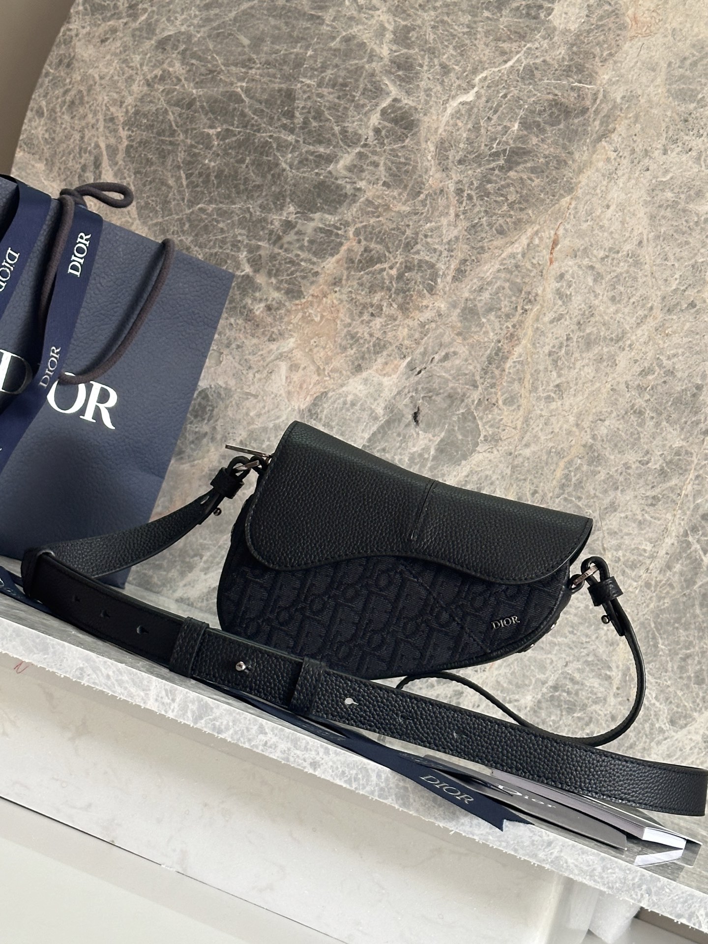 NO:395170,P This saddle bag is a new classic design with a modern structure. It is carefully crafted from black Oblique printed fabrics and other materials, decorated with a classic black grain cowhide magnetic flap with a hidden zipper closure. The interior is equipped with large compartments and insert bags to hold a variety of daily necessities. Mini styles are equipped with adjustable and removable leather shoulder straps for hand, shoulder or crossbody. Fabric fabrics, cowhides, lining fabrics, cowhides and decorative lines Main compartment with saddle flap Inner insert bag Magnetic flap with hidden zipper Adjustable and removable leather shoulder straps Metal cladding copper alloy Dior logo Internal embossed with Dior embossed logo Inside dust bag Made in Italy/Spain  *This product is produced in many countries. Please refer to the product label when you actually purchase the product. Dimensions 19.5 x 13.7 x 5.5 cm (Length x Height x Width) Main compartment can store 2 mobile phones Model: 93916 Black leather Black cloth Blue cloth, Dior, Dior, Dior, Cowhide19860909P 这款马鞍包以现代结构全新演绎经典设计.采用黑色 Oblique 印花面料等材质精心制作,饰以经典的黑色粒面牛皮革磁性翻盖,搭配隐藏式拉链开合.内部设有大号隔层和插袋,可收纳各种日常用品.迷你款式,搭配可调节、可拆卸的皮革肩带,可手提、肩背或斜挎. 面料织物,牛皮革 里料织物,牛皮革 装饰物及装饰线除外 主隔层搭配马鞍翻盖 内部插袋 磁性翻盖开合搭配隐藏式拉链 可调节、可拆卸的皮革肩带 正面饰以金属覆层铜合金 Dior 标志 内部饰有 Dior 压花标志 内含防尘袋 意大利/西班牙制造 *该款产品在多个国家生产,您实际购买的产品原产地请见产品标签. 尺寸19.5 x 13.7 x 5.5 厘米（长 x 高 x 宽） 主隔层可收纳 2 部手机 型号:93916黑皮 黑布 蓝布,迪奥,dior,dior,cowhide,Bag