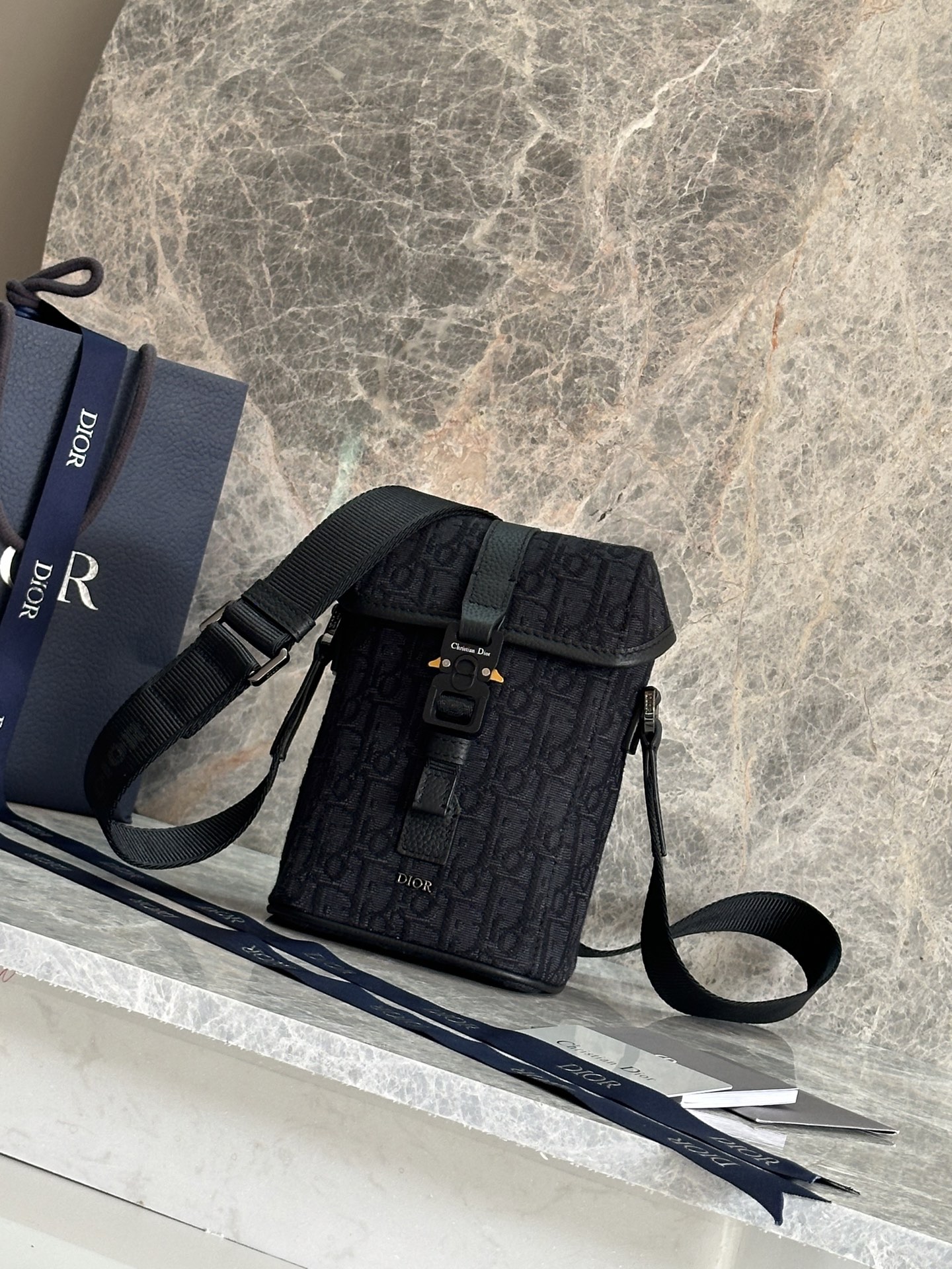 NO:395169,P This vertical flip messenger bag is a new product for the 2025 summer men's clothing series. The modern and fashionable design fully highlights the high-order style of Dior and enhances the style of Dior Hit The Road series. It is carefully crafted from beige and black Oblique printed fabrics, decorated with black grain cowhide details to enhance the style, and the front is embellished with Dior logo. The flip is decorated with aluminum buckles and embellished with CD initials, with main compartment and a socket bag. Mini style, paired with adjustable shoulder straps, adds the finishing touch to various casual outfits. Main body cotton, technology fabric, cowhide with leather Liquid tech fabric, cotton, cowhide with leather Main compartment is decorated with CD mini aluminum buckle Internal plugs Adjustable Christian Dior logo nylon jacquard and cowhide shoulder straps  Front is decorated with metal clad copper alloy Dior logo Dior embossed logo Inside dust bag Dimensions 13 x 20 x 7 cm (L x H x W) Main compartment can accommodate 2 mobile phones Strap length 83.5 - 129 cm Strap top to top of handbag length 34 - 57.5 cm Weight 400 g Model 93917 Black cloth Blue cloth, Dior, Dior, Dior, Cowhide19860909P 这款竖版翻盖信使包是二零二五夏季男装系列新品,现代时尚的设计充分突显 Dior 的高订风格,提升 Dior Hit The Road 系列的格调.采用米色和黑色 Oblique 印花面料等材质精心制作,饰以黑色粒面牛皮革细节提升格调,正面点缀以 Dior 标志.翻盖饰以铝扣,点缀以 CD 首字母,设有主隔层和一个插袋.迷你款式,搭配可调节肩带,可为各式休闲装扮增添点睛之笔. 主体棉,科技面料,牛皮革 里料科技面料,棉,牛皮革 主隔层搭配翻盖,饰以 CD 标志迷你铝扣 内部插袋 可调节的 Christian Dior 标志尼龙提花和牛皮革肩带 正面饰以金属覆层铜合金 Dior 标志 内部饰有 Dior 压花标志 内含防尘袋 尺寸13 x 20 x 7 厘米（长 x 高 x 宽） 主隔层可收纳 2 部手机 肩带长度83.5 - 129 厘米 肩带顶端至手袋顶端长度34 - 57.5 厘米 重量400 克 型号93917黑布 蓝布,迪奥,dior,dior,cowhide,Bag