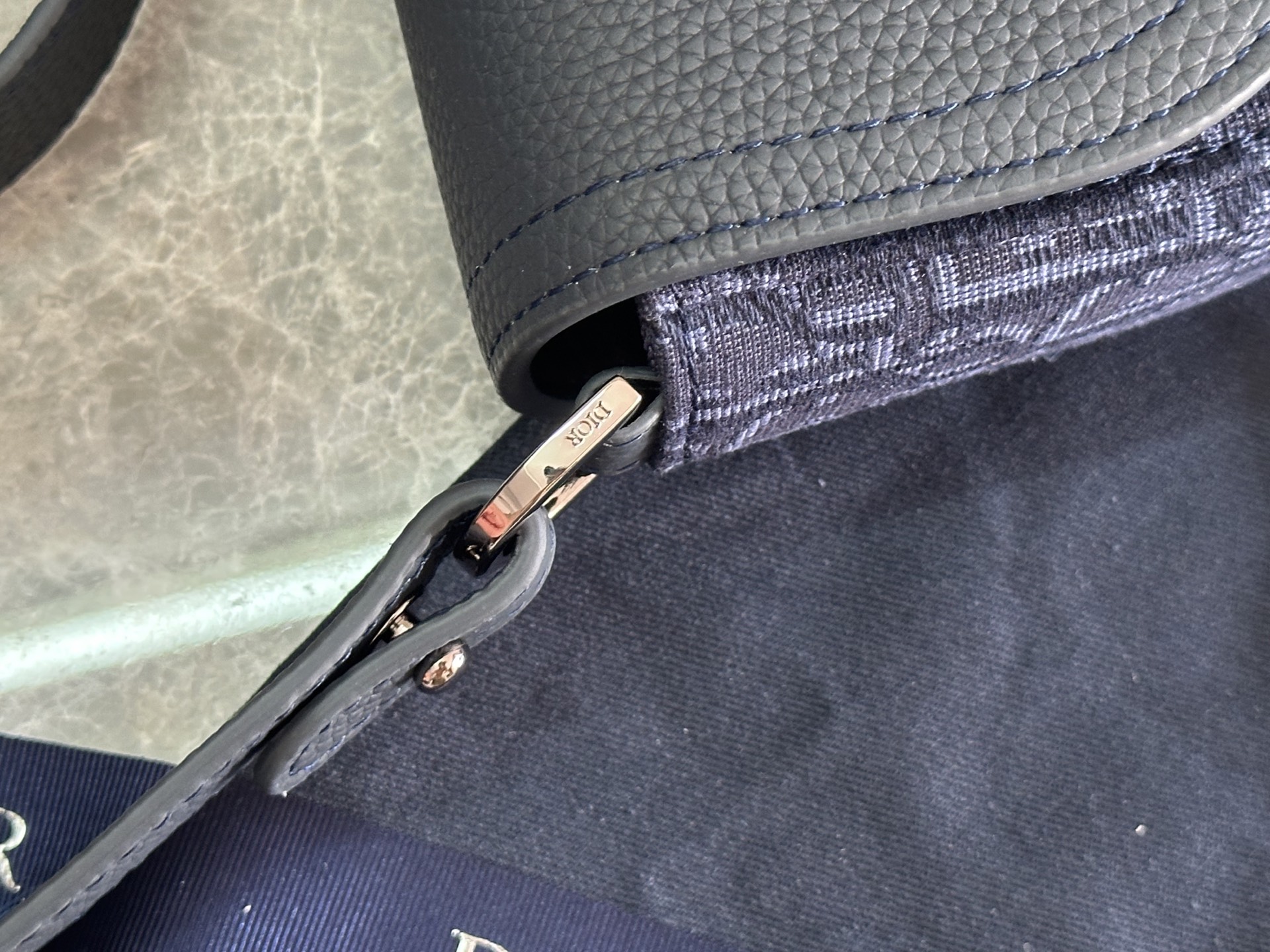   这款马鞍手拿包附有肩带，是二零二五春季男装系列推出的新款单品，采用时尚的设计，彰显精致的优雅气质，为