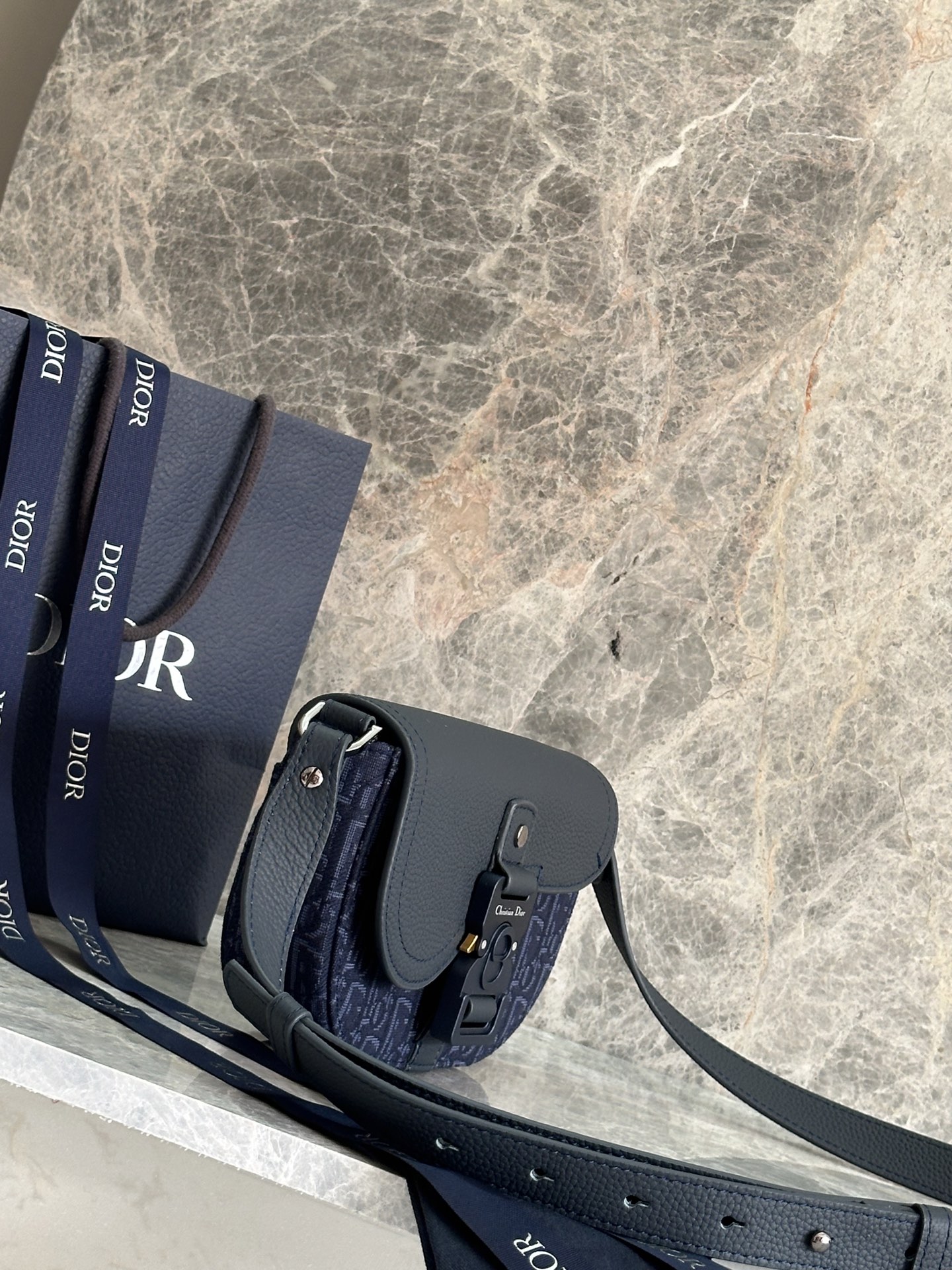   这款马鞍手拿包附有肩带，是二零二五春季男装系列推出的新款单品，采用时尚的设计，彰显精致的优雅气质，为