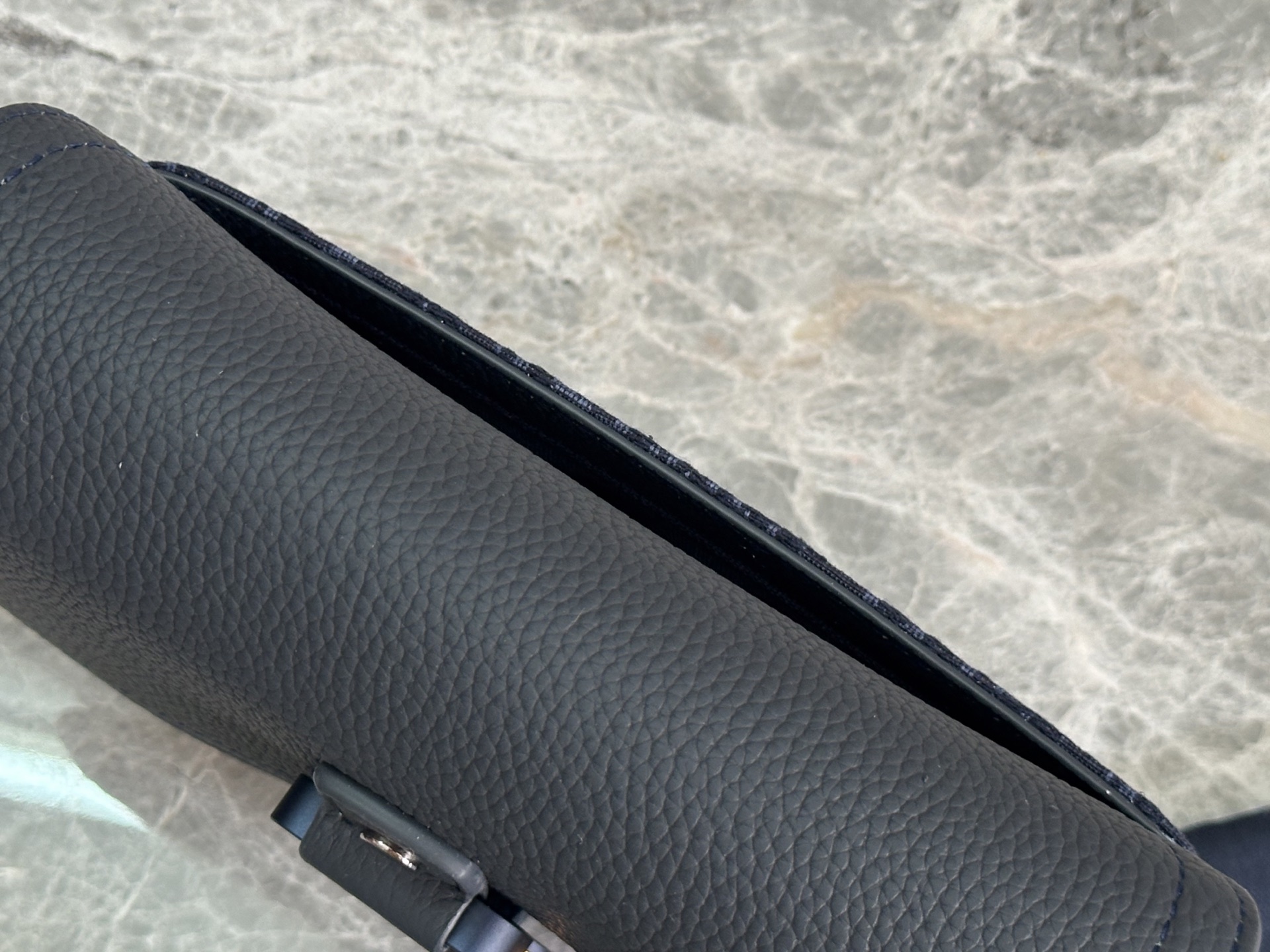   这款马鞍手拿包附有肩带，是二零二五春季男装系列推出的新款单品，采用时尚的设计，彰显精致的优雅气质，为