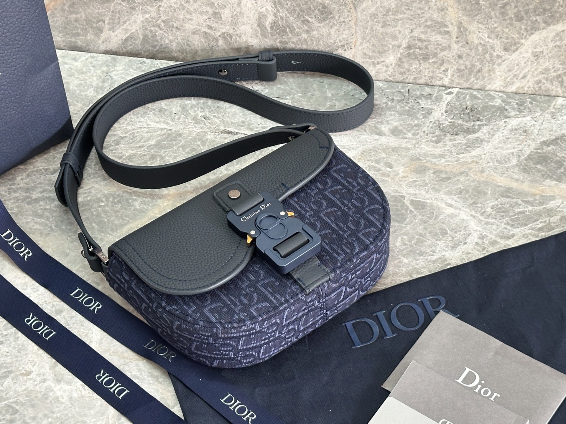   这款马鞍手拿包附有肩带，是二零二五春季男装系列推出的新款单品，采用时尚的设计，彰显精致的优雅气质，为