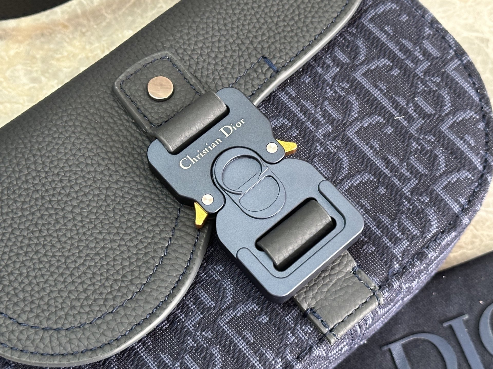   这款马鞍手拿包附有肩带，是二零二五春季男装系列推出的新款单品，采用时尚的设计，彰显精致的优雅气质，为